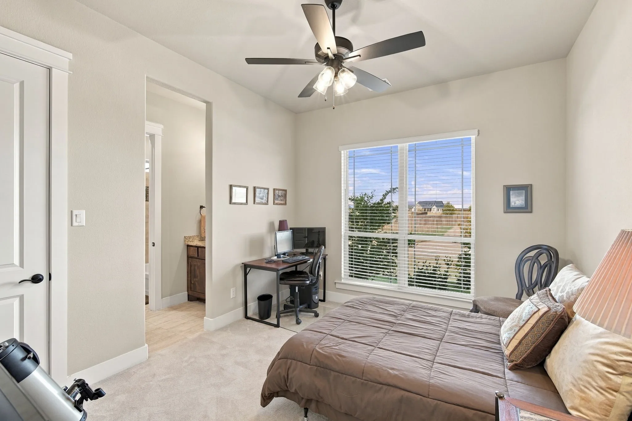 Secondary bedroom has a Jack-and Jill bath, ceiling fan light fixture, blinds, and a walk in closet with lighting.