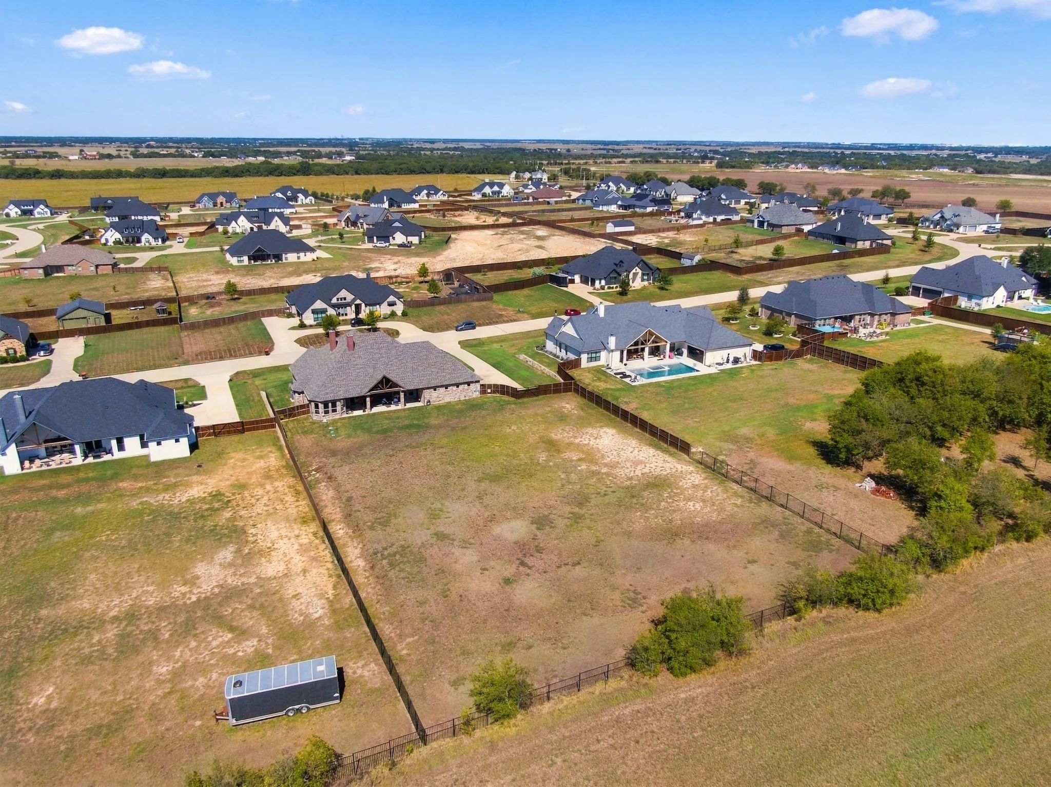 Fully fenced yard with wood on the sides and iron at the back to take in the farm land view. Nice homes all around.