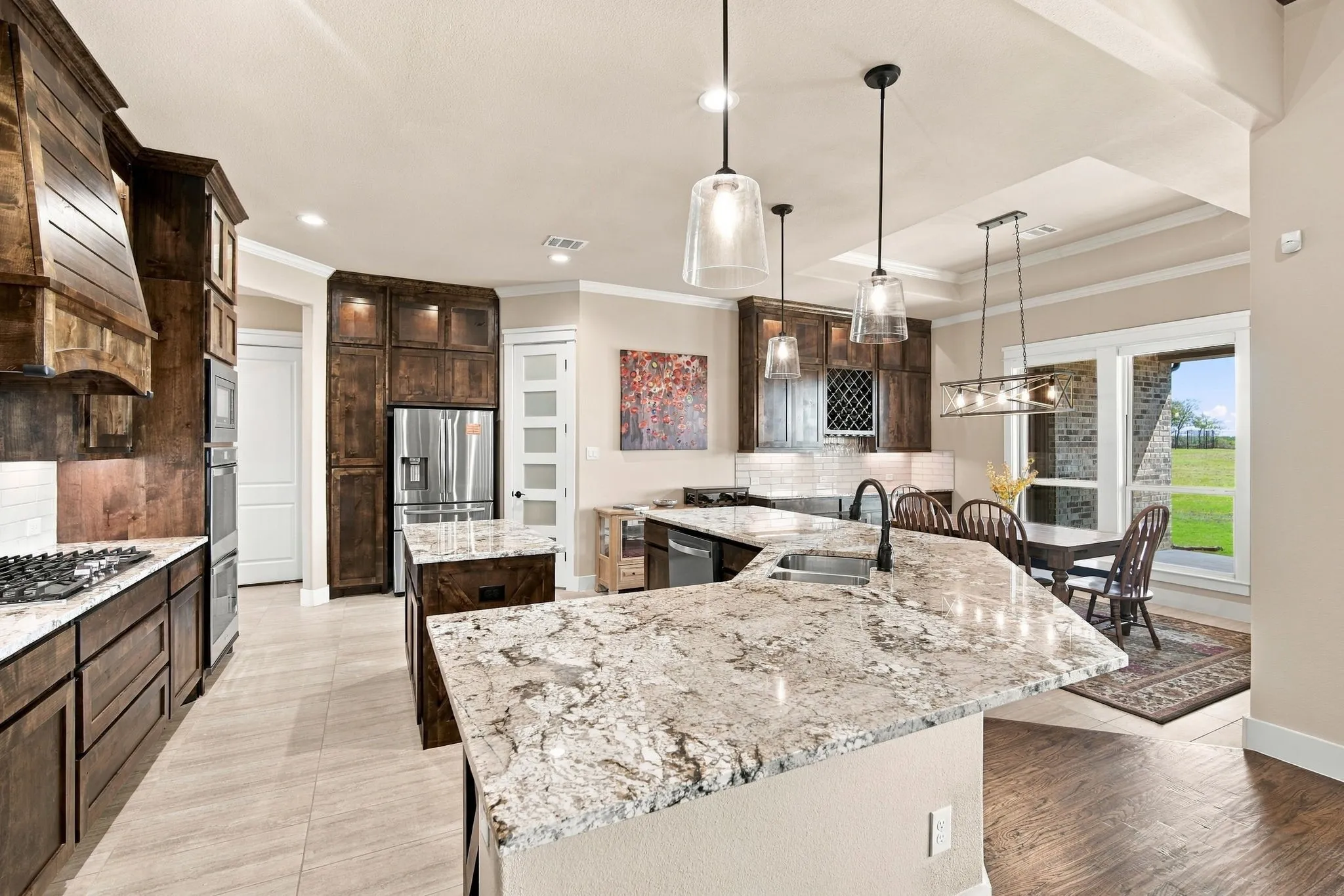 Gourmet kitchen features double ovens, a 5 burner gas cooktop, spacious island and stainless steel appliances.