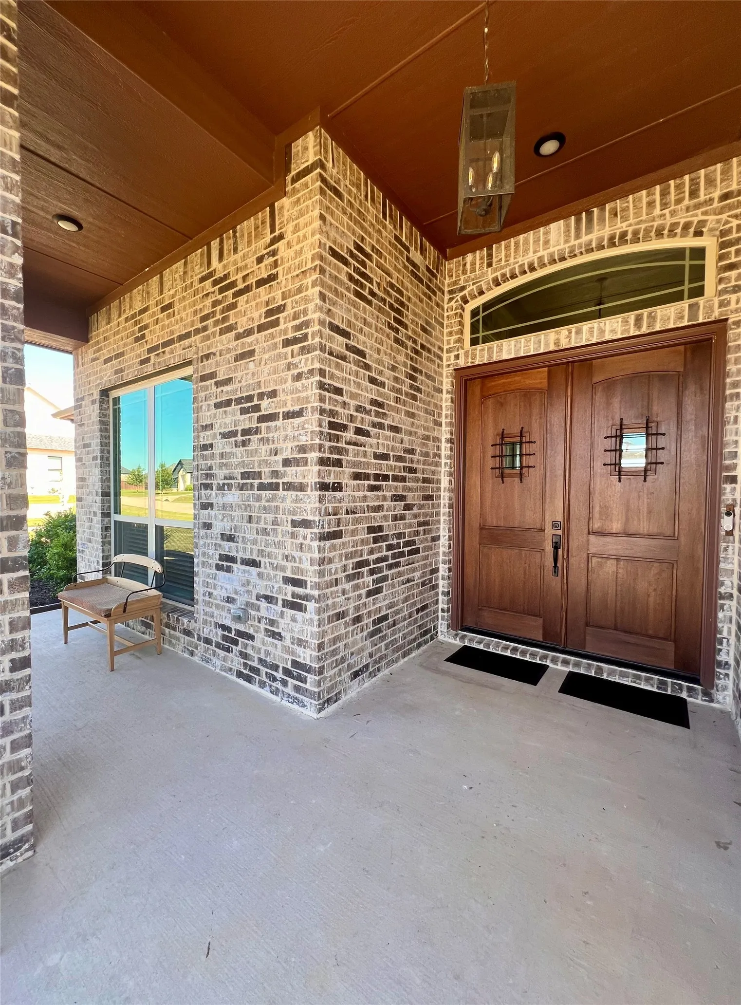 Great way to meet your guests on this covered entry with double wood doors and a pretty arched transom window.