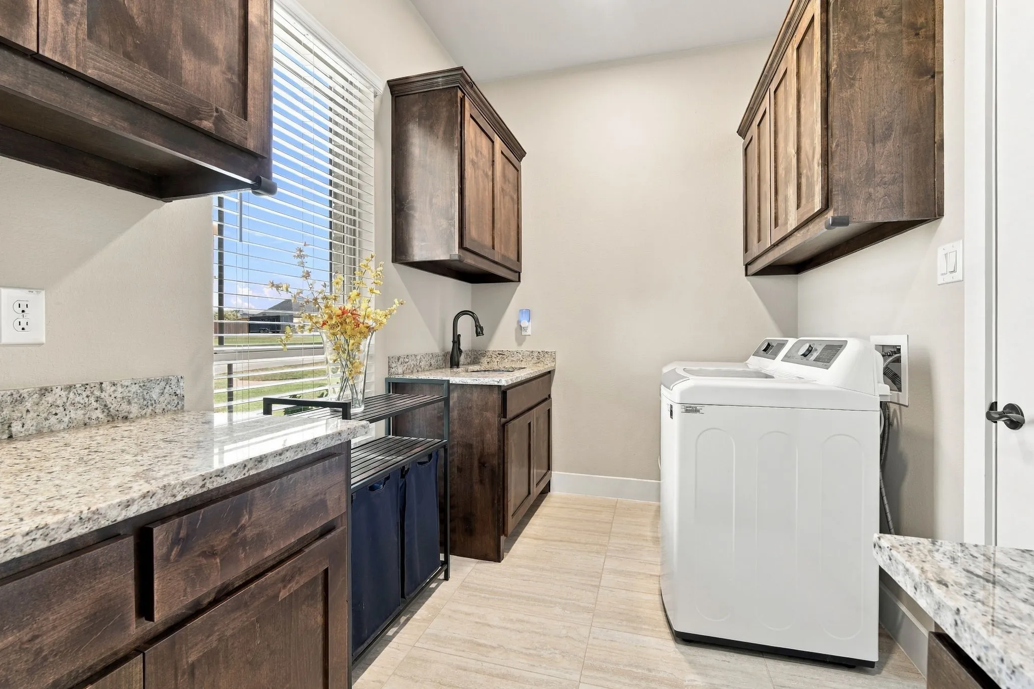 Love this spacious laundry room with granite countertops, a utility sink, plenty of folding space and tile flooring.