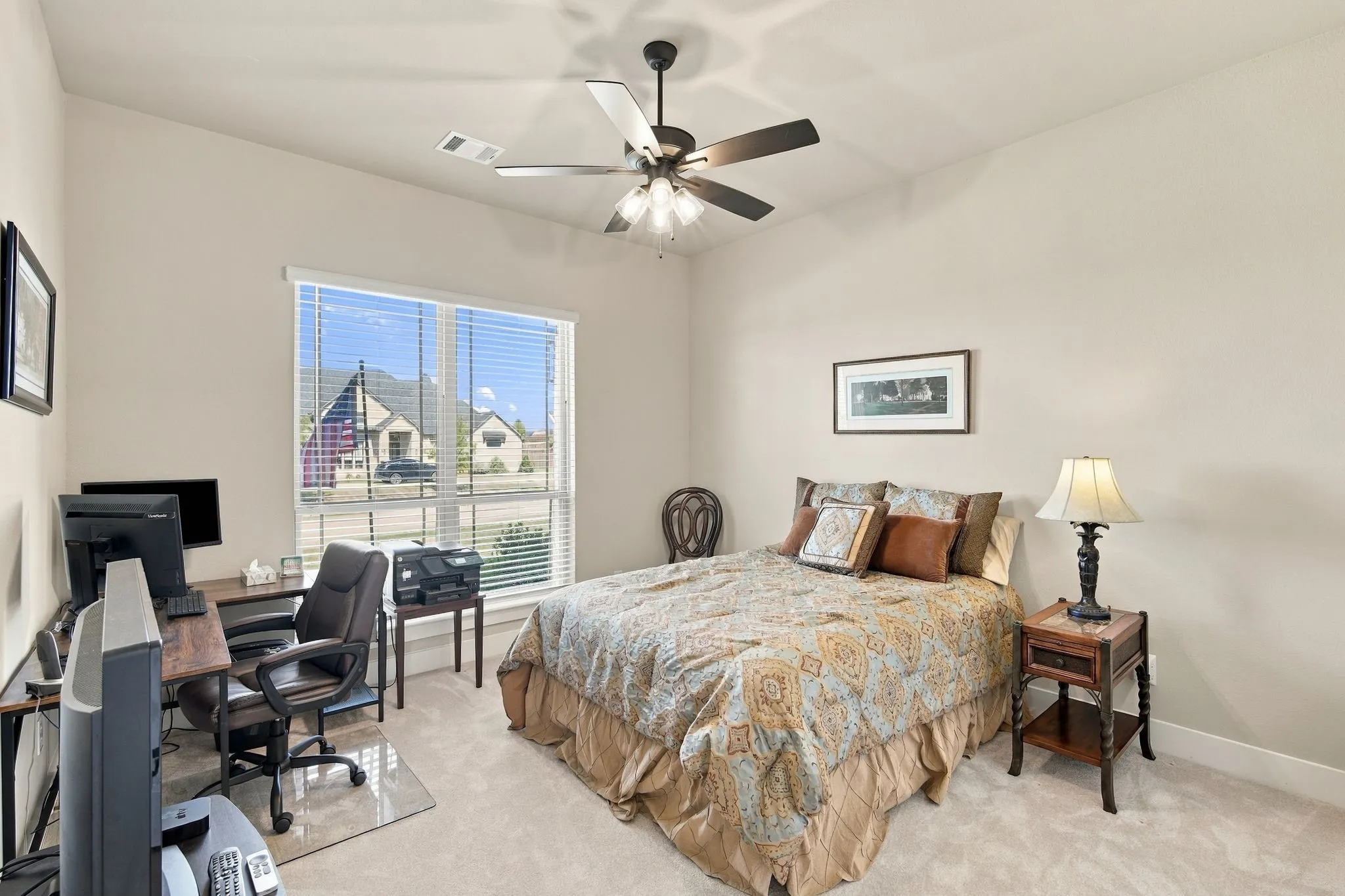 Spacious secondary bedroom with a vaulted ceiling with a ceiling fan, large window with blinds and a walk in closet with lighting.