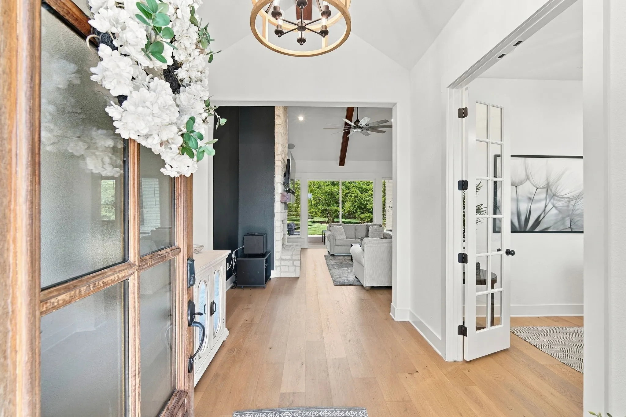 Vaulted ceilings and wood flooring with a decorative light fixture adorn the foyer.