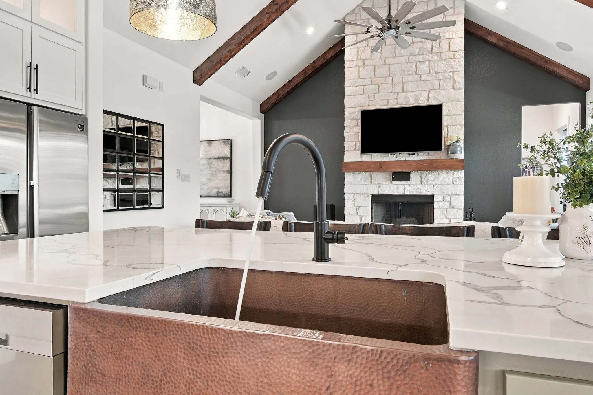 Copper farmhouse sink with a matte black faucet, integrated into a quartz countertop.