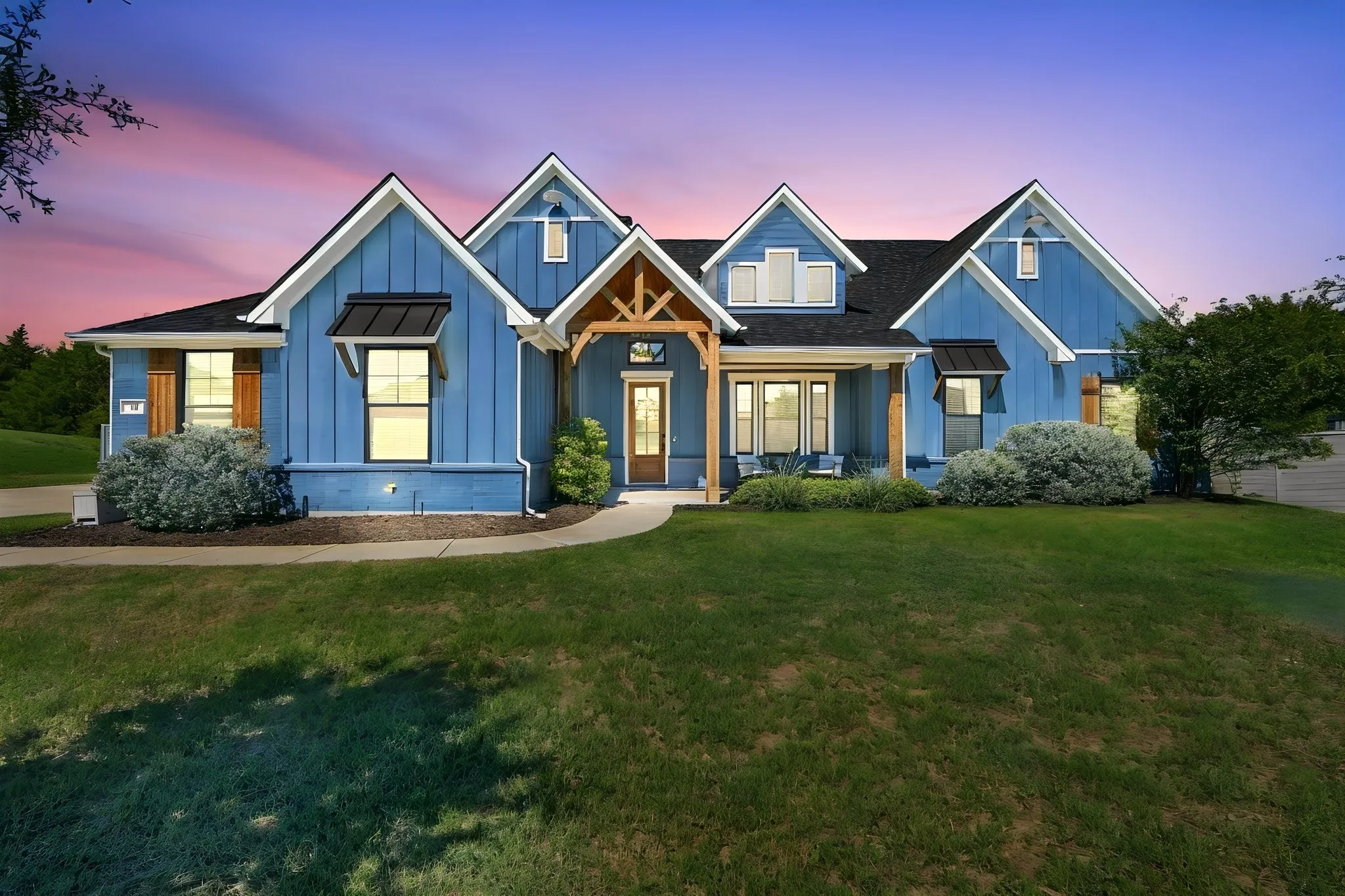 Board and batten siding, multiple gables, covered porch with cedar accents and black metal window awnings really make this home stand out.