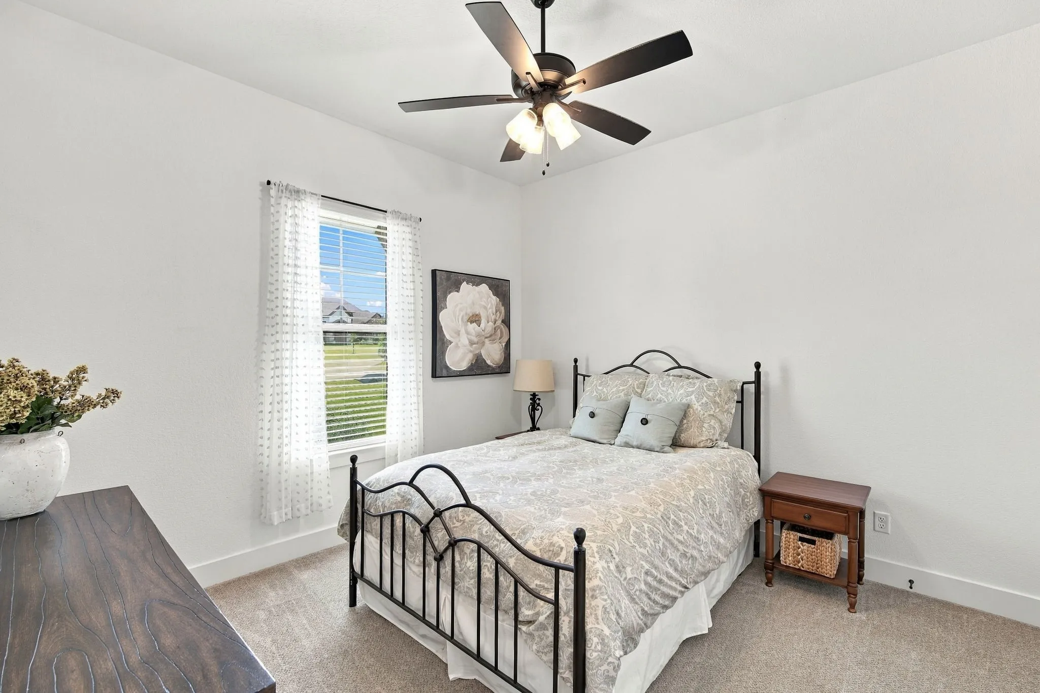 The secondary bedroom is a good size and has a ceiling fan, blinds, and neutral carpet flooring