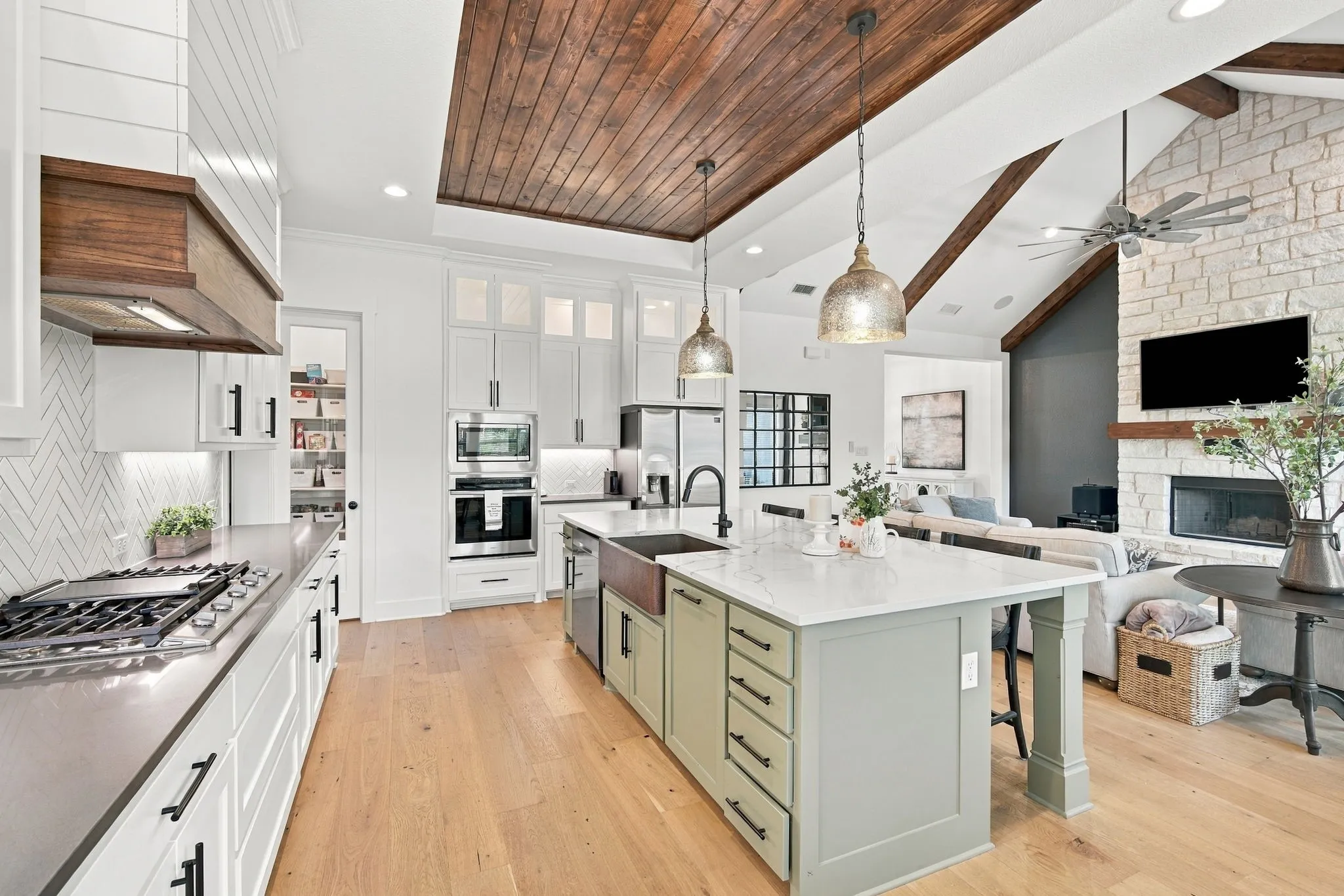 Open-concept floor plan with a large central island with seating, a walk in pantry  and unique pendant lighting.