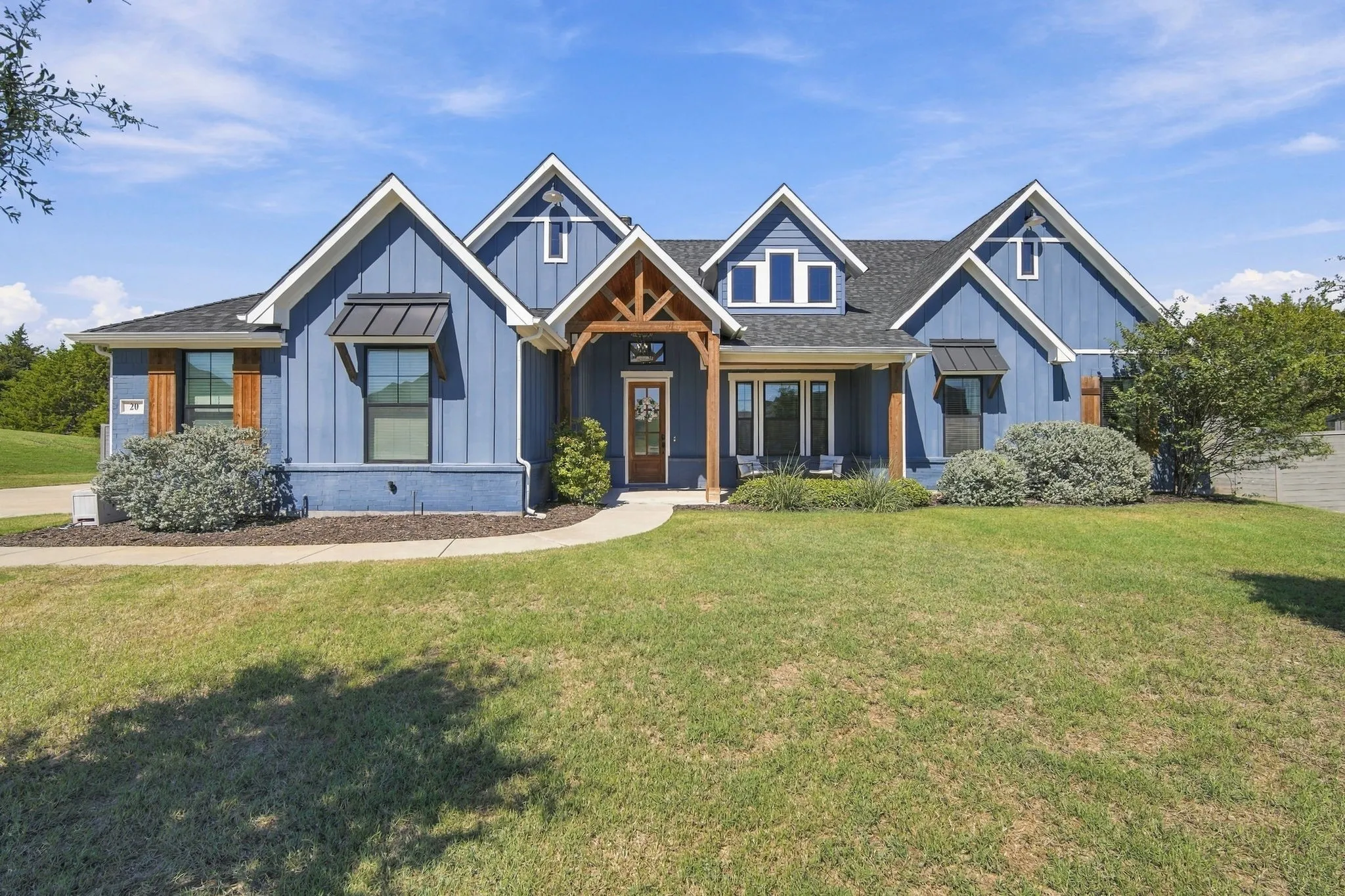 Eye catching blue, board and batten home with white trim and decorative metal awnings.