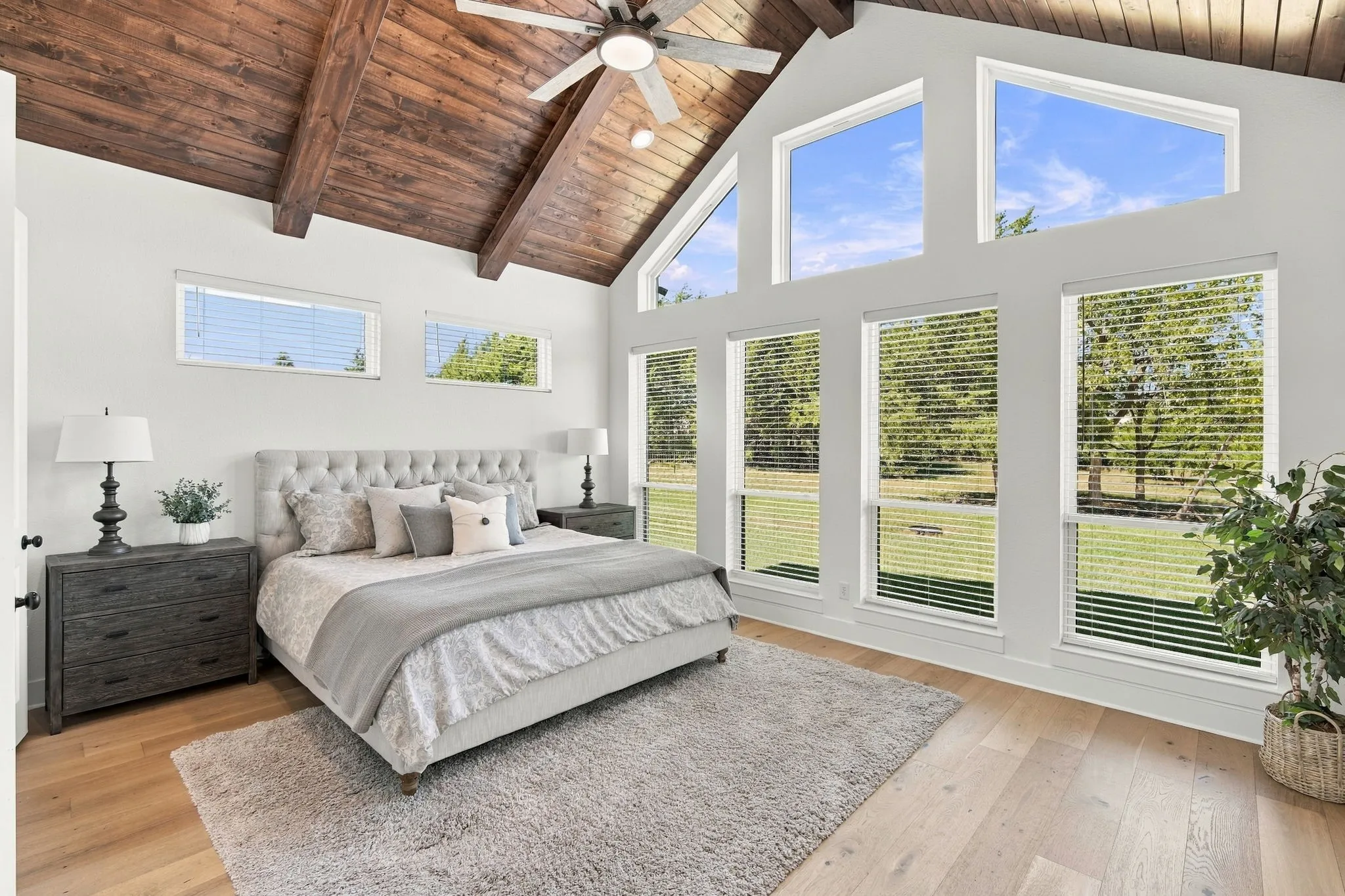 Vaulted wood-finish ceiling with exposed beams, wood flooring, with windows letting in natural light.
