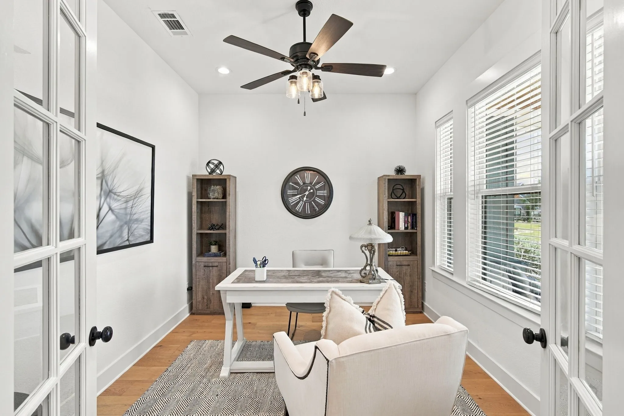 The dedicated office has hardwood flooring, recessed lighting, a ceiling fan and French glass doors.