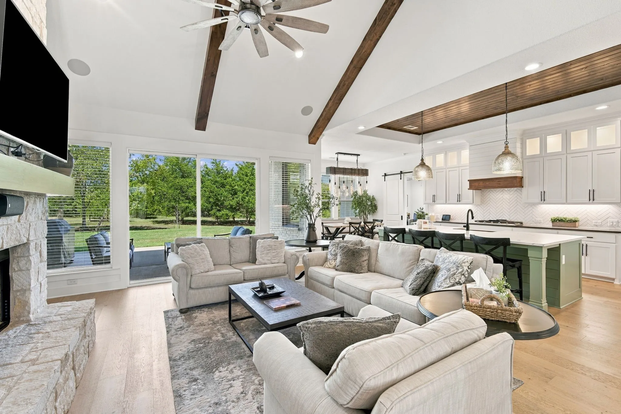 The living room has a cathedral ceiling with wood beams and surround sound speakers.