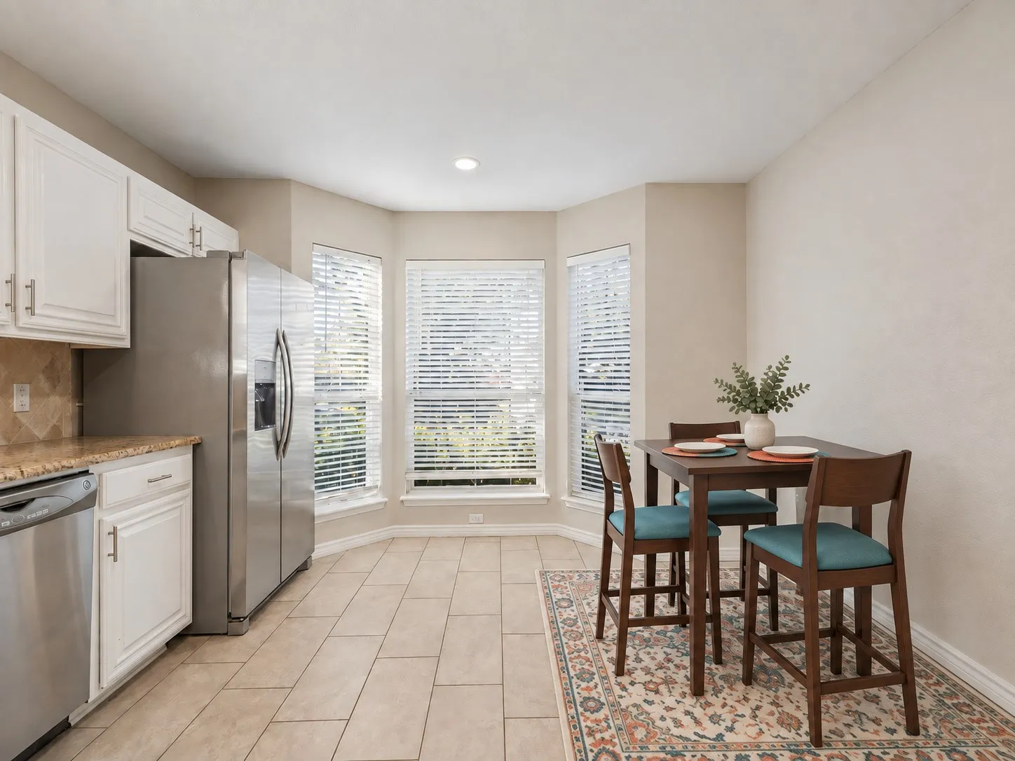 Kitchen featuring white cabinetry, stainless steel appliances, granite countertops, and tiled flooring