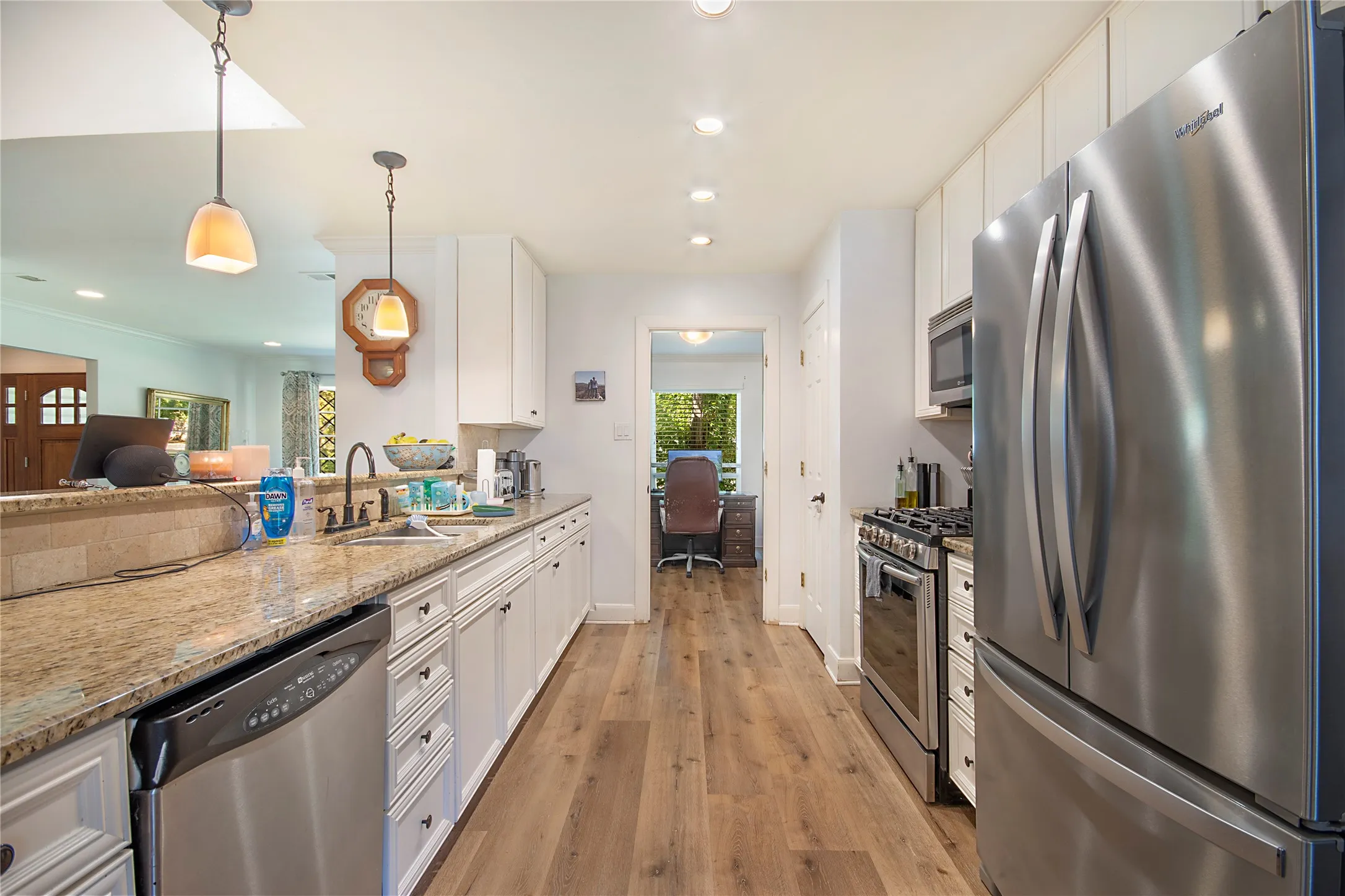 Kitchen featuring wood-finish flooring, white cabinetry, a stainless steel refrigerator, stainless steel range, and a granite-style countertop