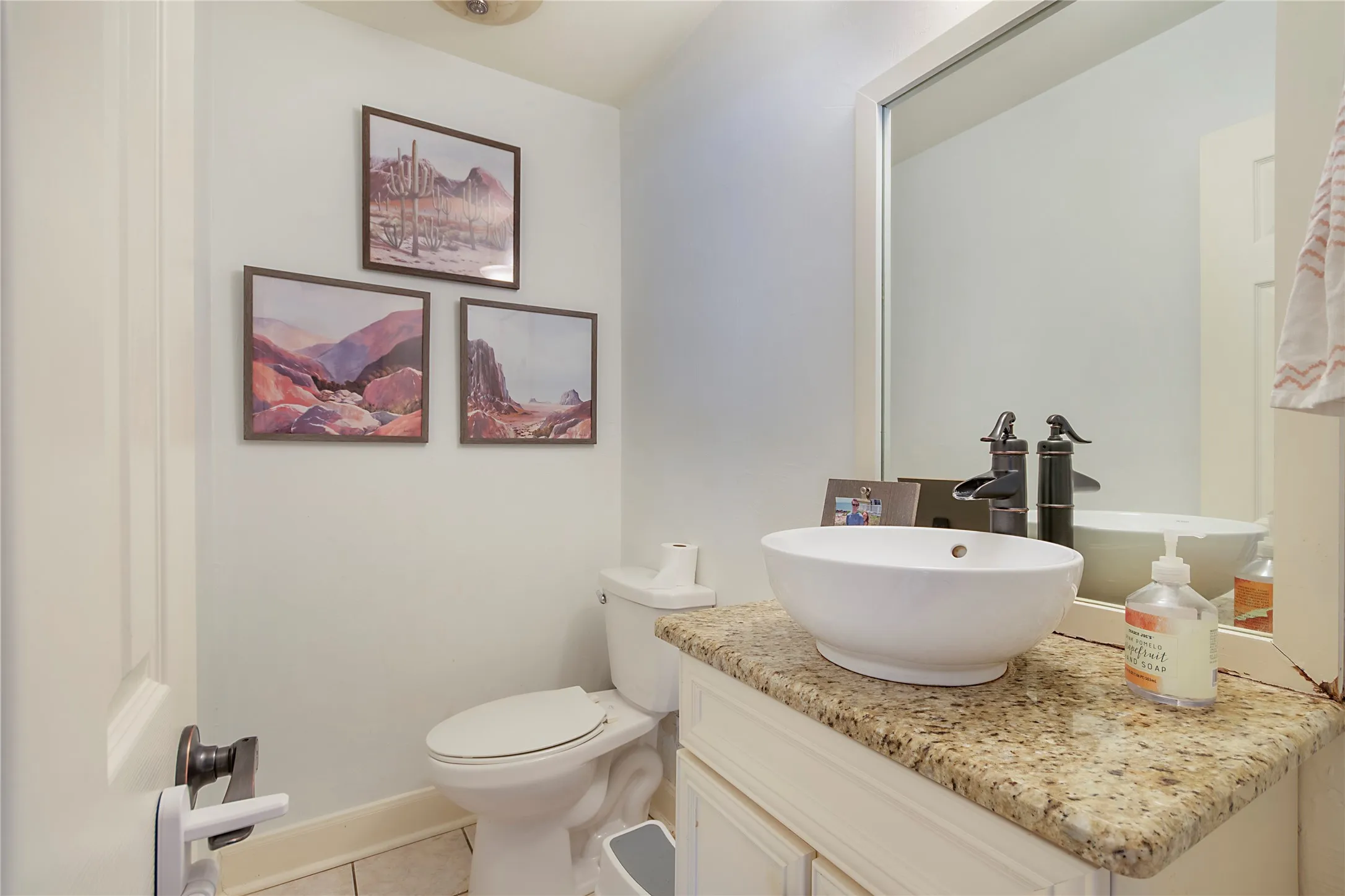 Granite countertop, vessel sink, oil-rubbed bronze faucet, built-in vanity cabinetry, and tile flooring