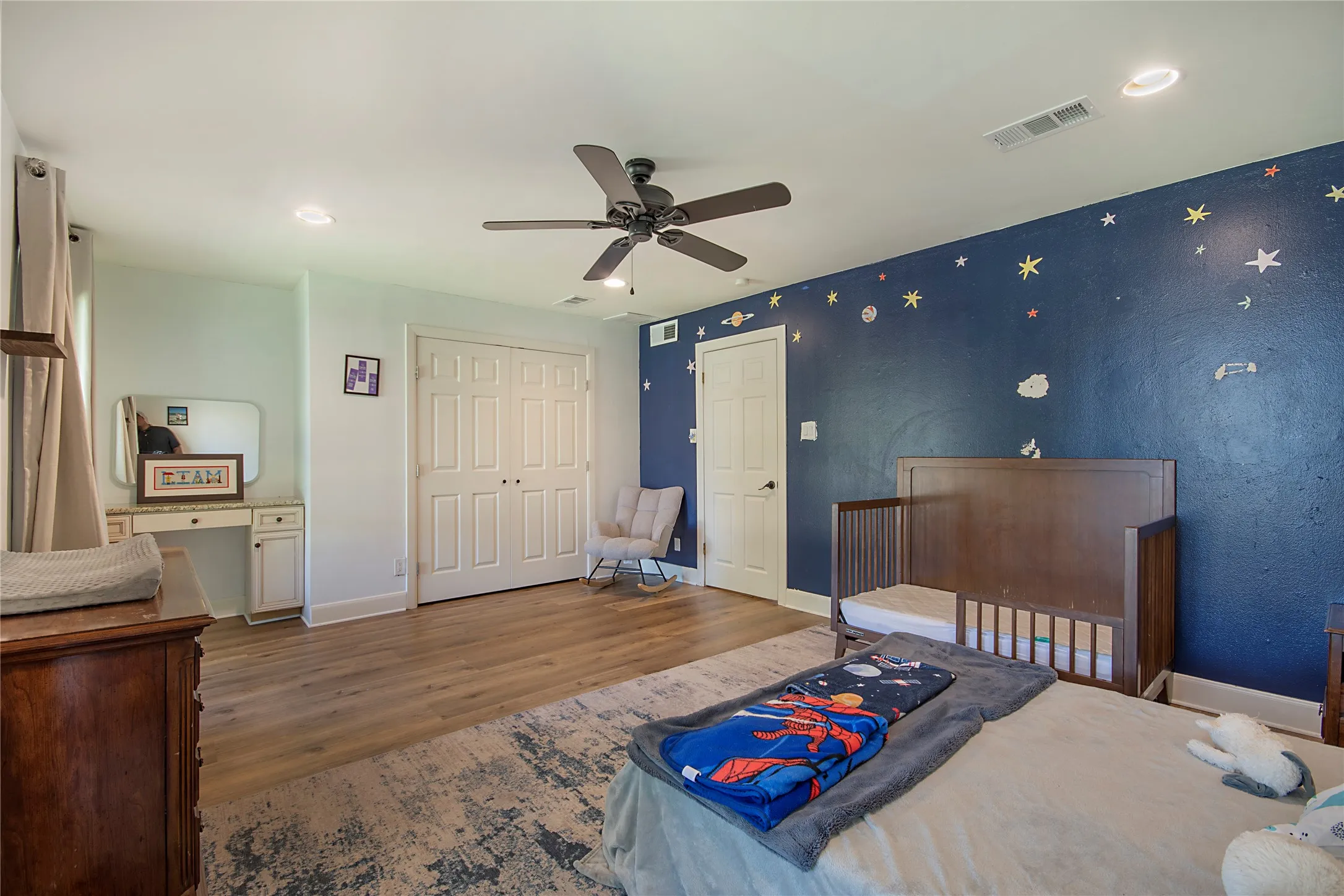 Recessed ceiling lighting, wood-finish flooring, ceiling fan, white paneled doors, and built-in vanity with countertop