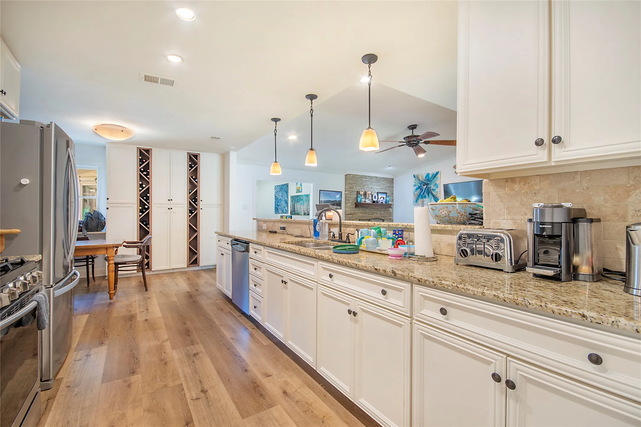 Kitchen featuring light wood-finish flooring, white cabinetry with dark hardware, a stone backsplash, and recessed lighting