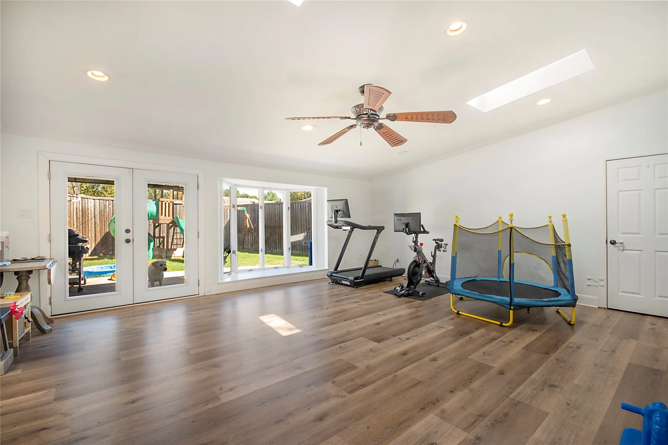 Spacious room featuring wood-finish flooring, recessed lighting, and a ceiling fan
