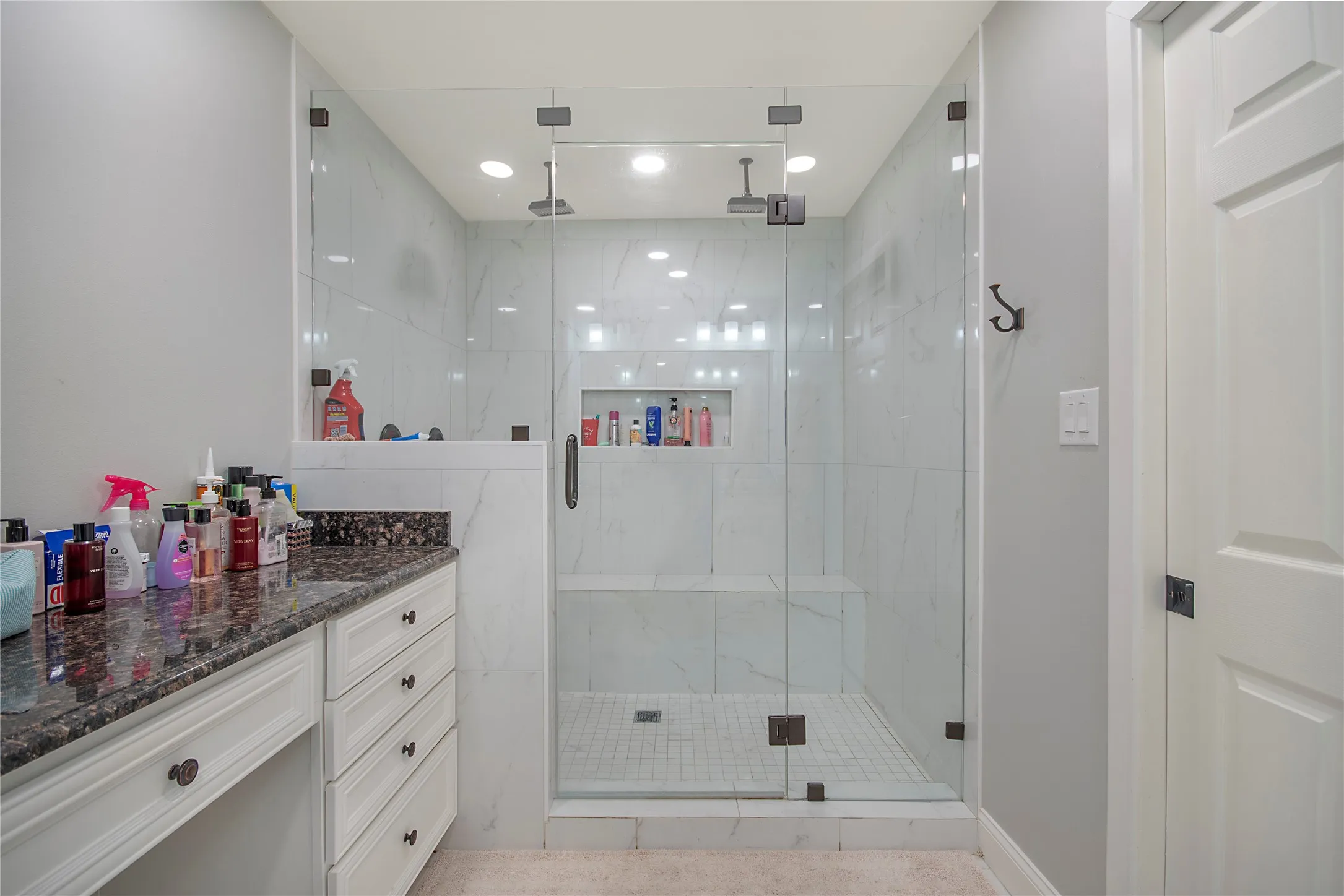 Walk-in shower with clear glass enclosure, white tile walls, and a built-in bench