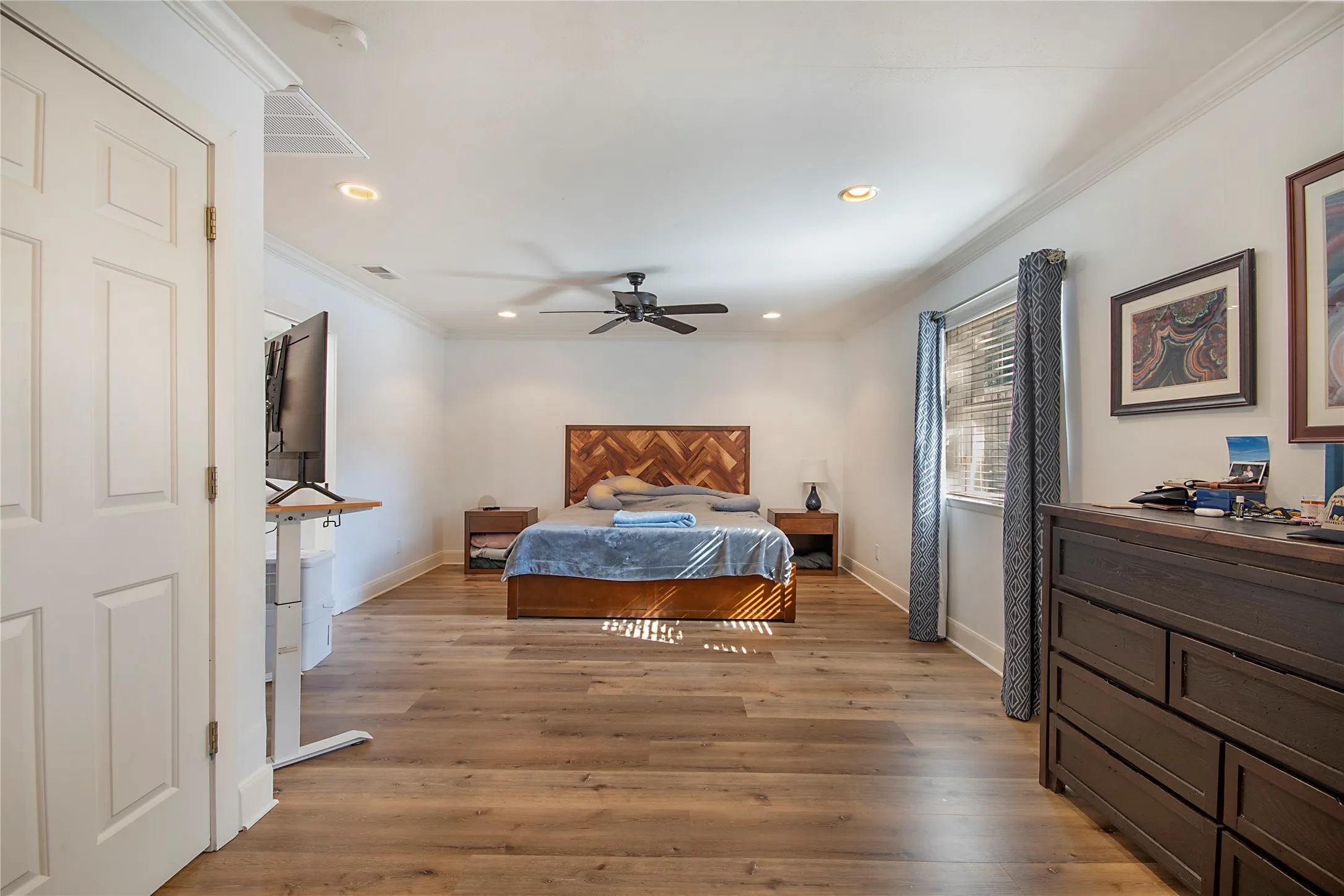 Spacious room featuring wood-finish flooring, recessed lighting, crown molding, and a ceiling fan