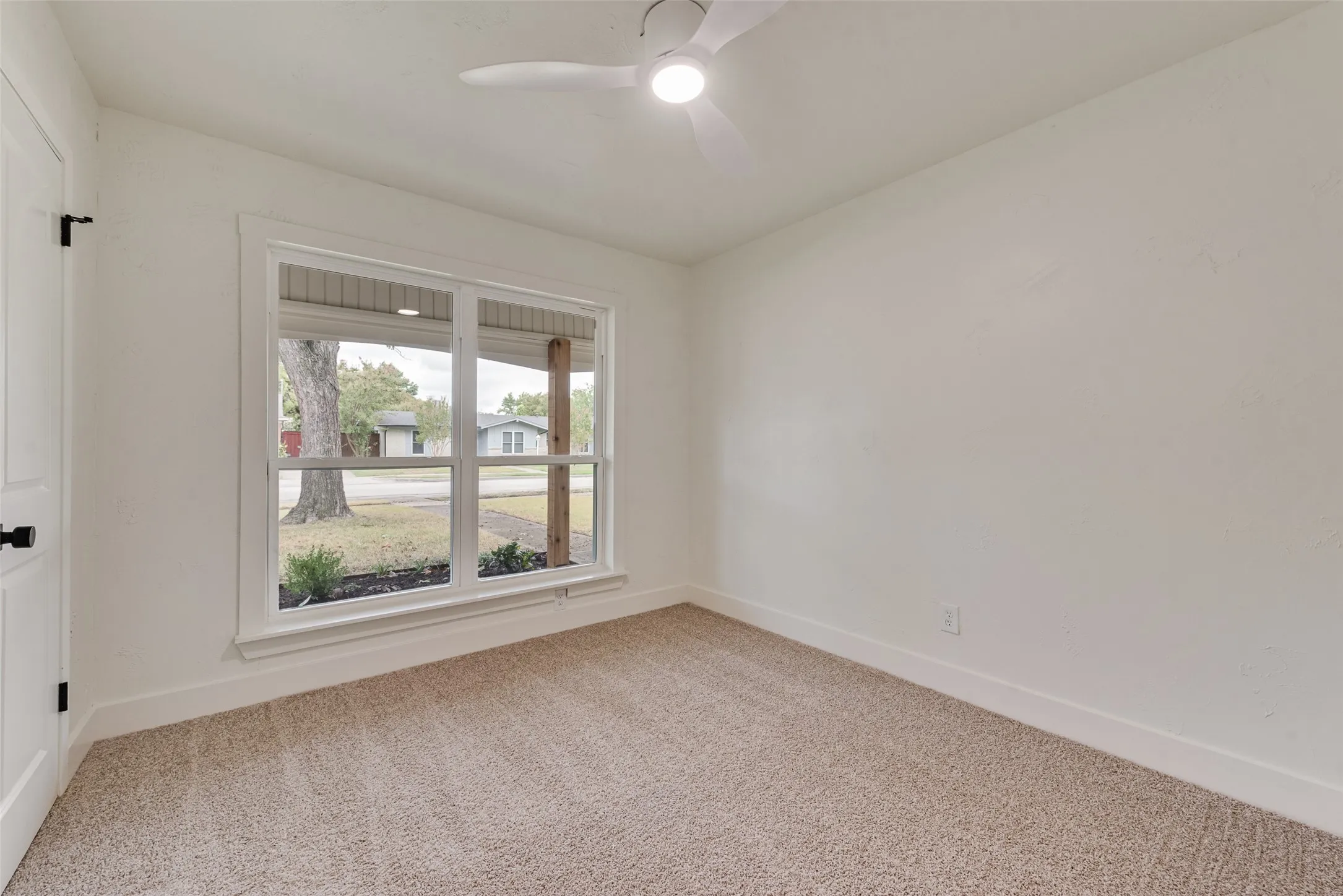 Additional secondary bedroom with new carpet and a large window.
