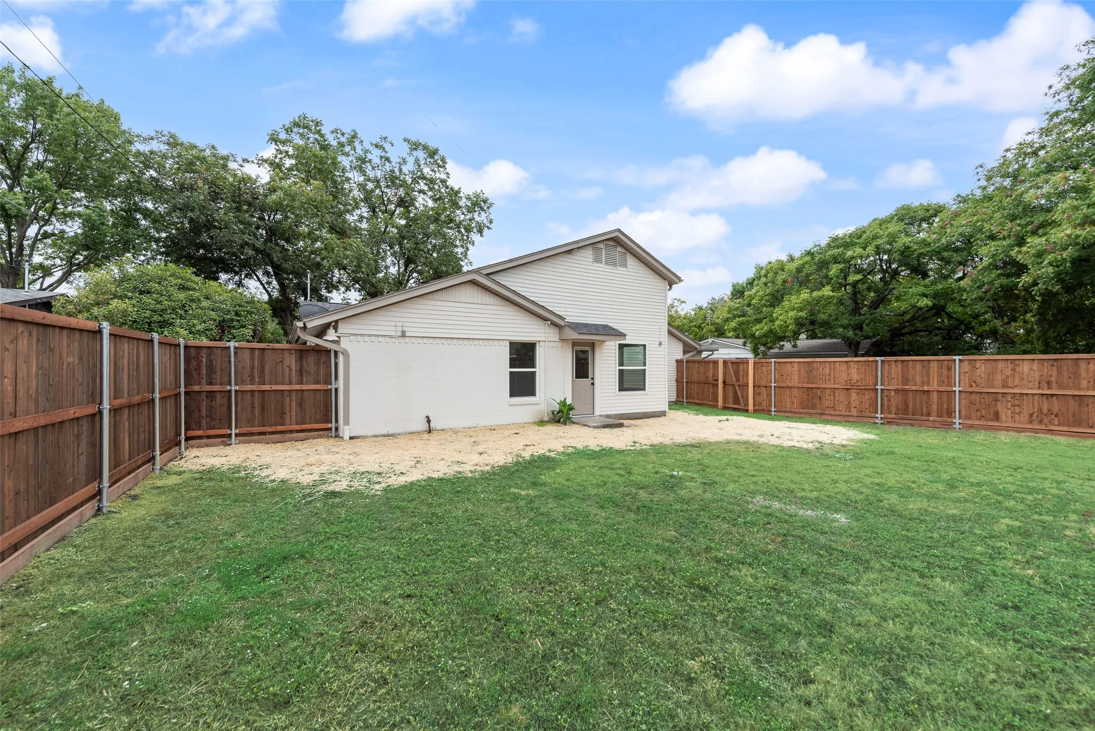 Fenced backyard with lawn space for relaxing, gardening, or pets.