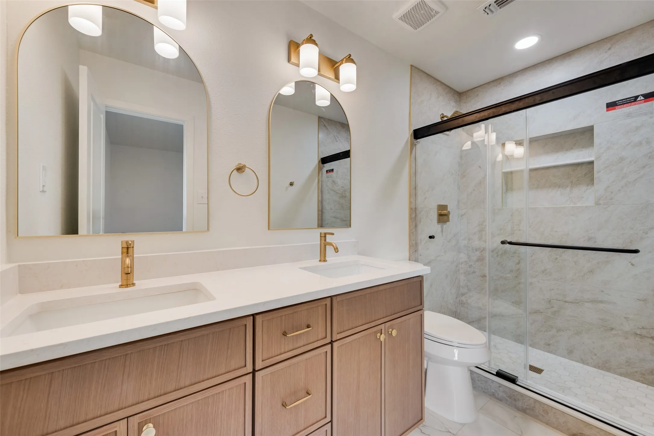 Primary bath features an extended vanity and glass-enclosed shower.