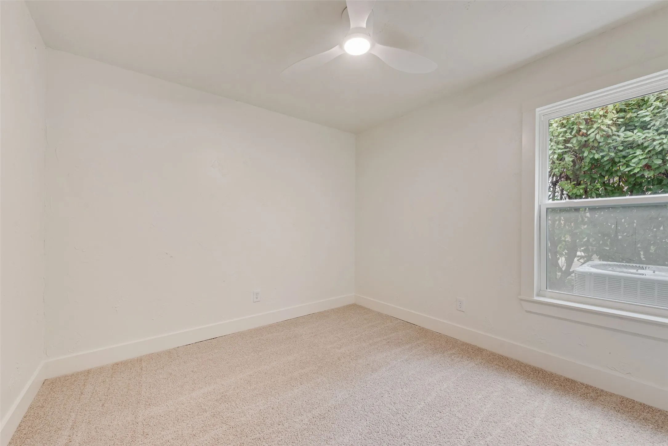 Bright secondary bedroom with new carpet and natural light.