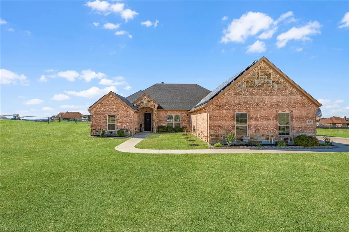 Impressive curb appeal featuring timeless brick-and-stone architecture, distinctive rooflines, manicured landscaping, and a spacious front lawn.