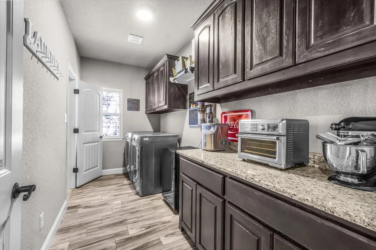 Laundry Room: Spacious laundry room offers extensive upper and lower cabinetry, granite counter space, durable tile flooring, and room for full-size appliances.