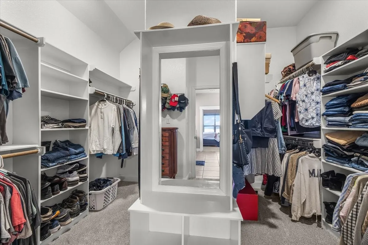 Primary Walk-In Closet: Generously sized walk-in closet features extensive built-in shelving and hanging space, plus a center storage unit with full-length mirror and bench.