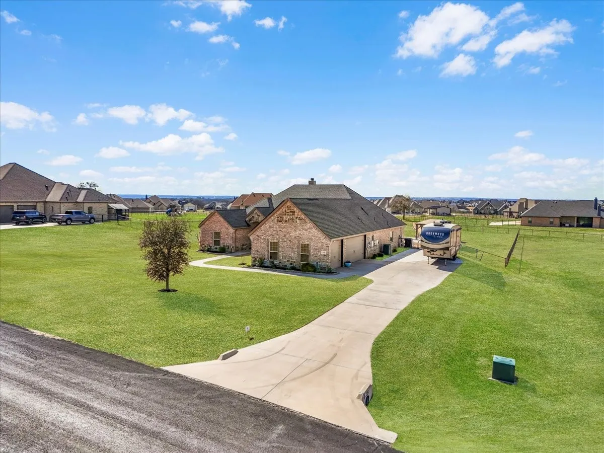 Expansive concrete driveway offering generous parking space, including room for an RV, boat, or additional vehicles. The three-car garage, beautiful brick-and-stone exterior, and spacious grounds add to the property's appeal.