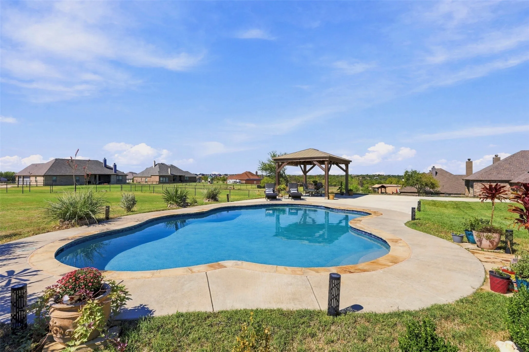Sparkling in-ground pool overlooking the home's covered back patio, offering a welcoming space for outdoor dining, entertaining, and relaxation.