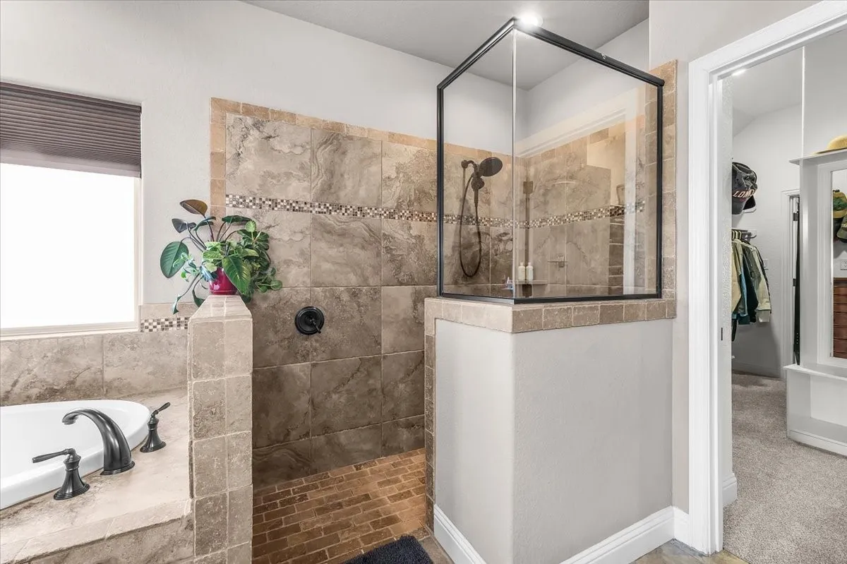 Primary Bathroom: Separate walk-in shower features extensive tilework, glass enclosure, decorative mosaic accents, and convenient access to the adjoining closet area.
