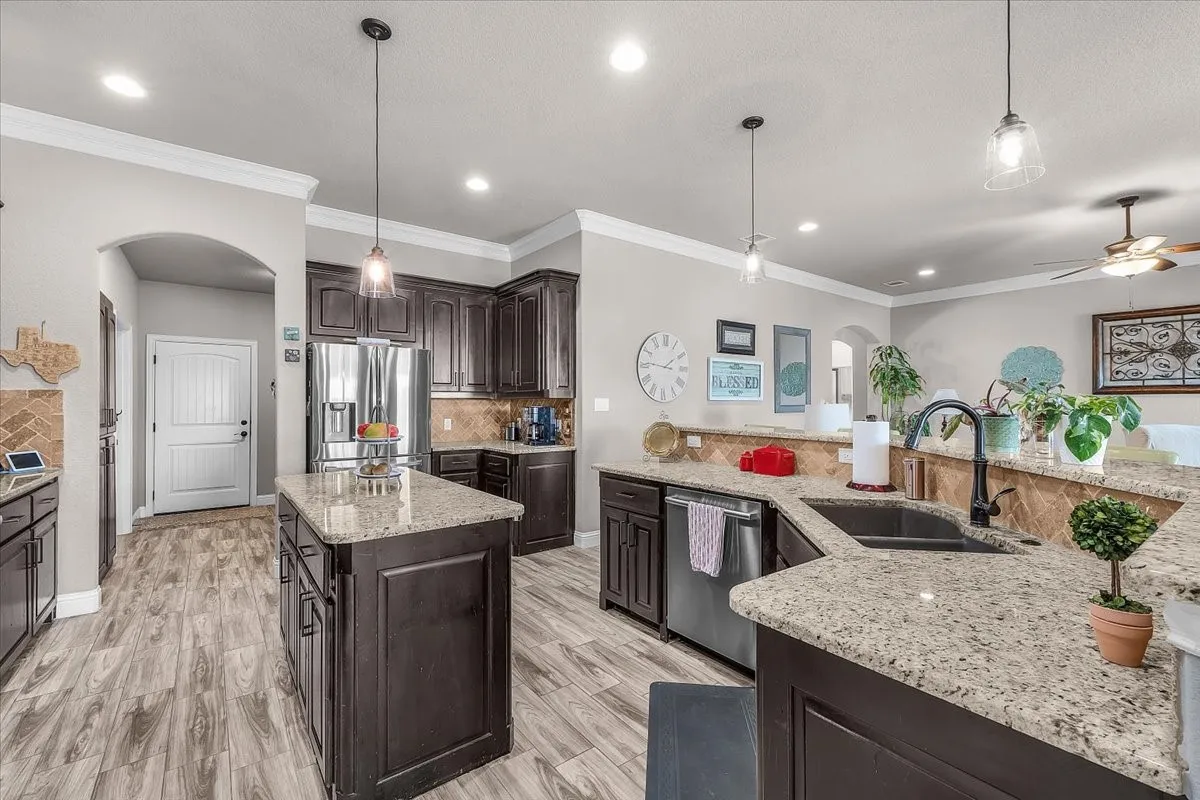 Kitchen: Well-equipped kitchen features granite countertops, dark wood cabinetry, stainless steel appliances, a center island, and an additional peninsula with sink and ample workspace.