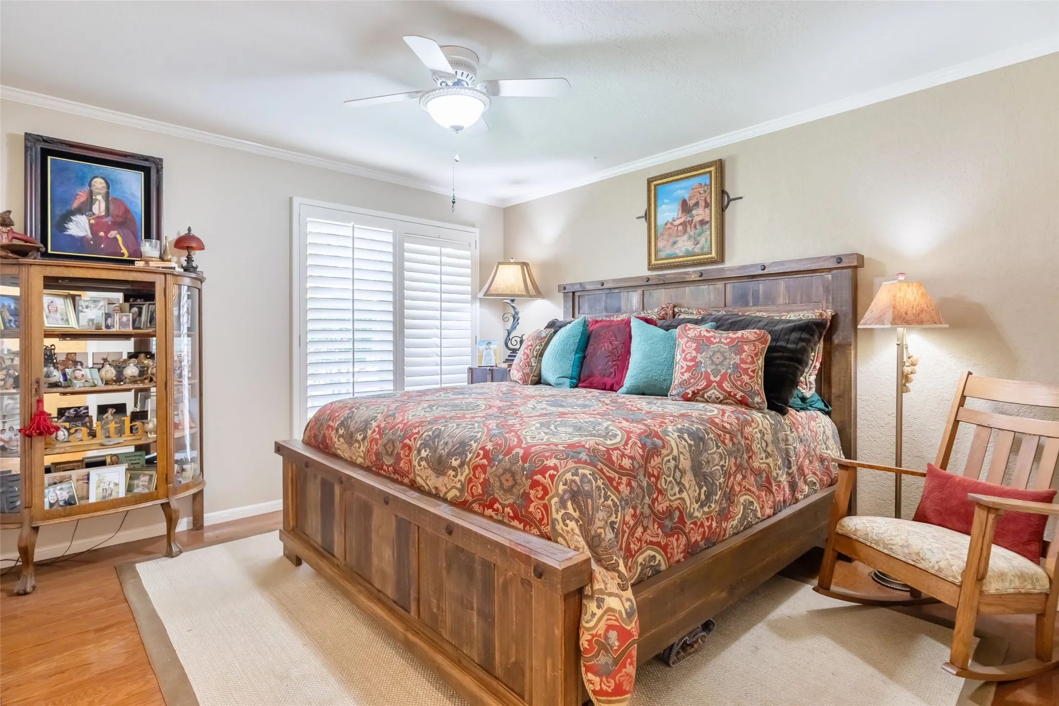 Wood-finish flooring, crown molding, ceiling fan with integrated lighting, and window with plantation shutters