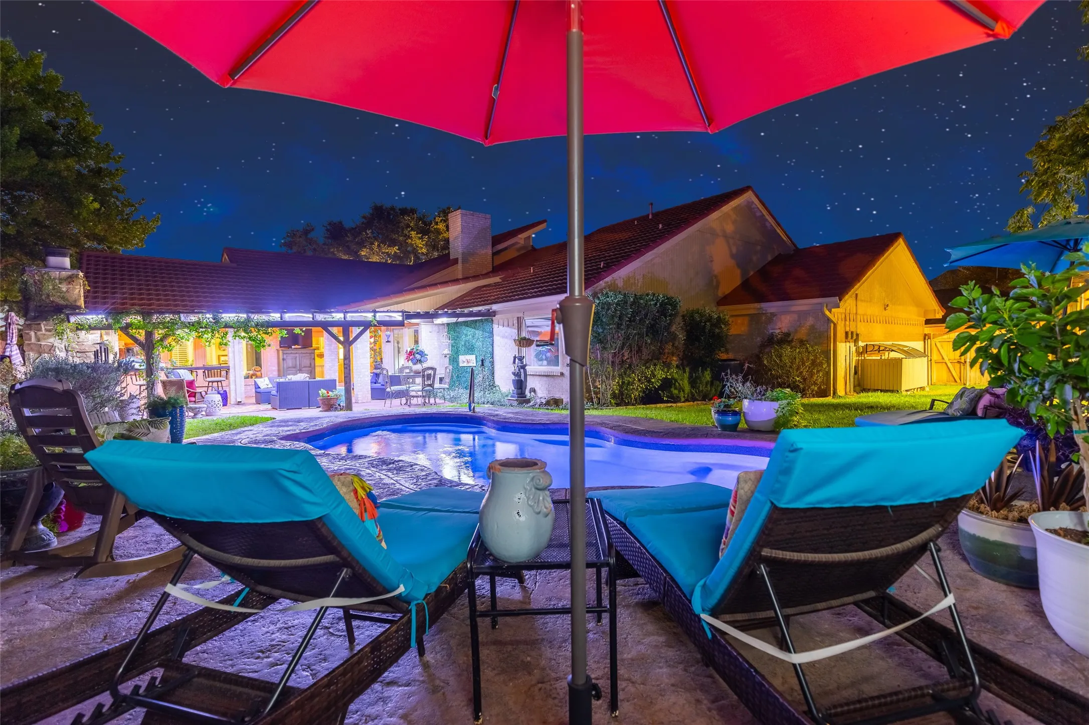 Curved in-ground pool with integrated lighting, surrounded by stamped concrete patio