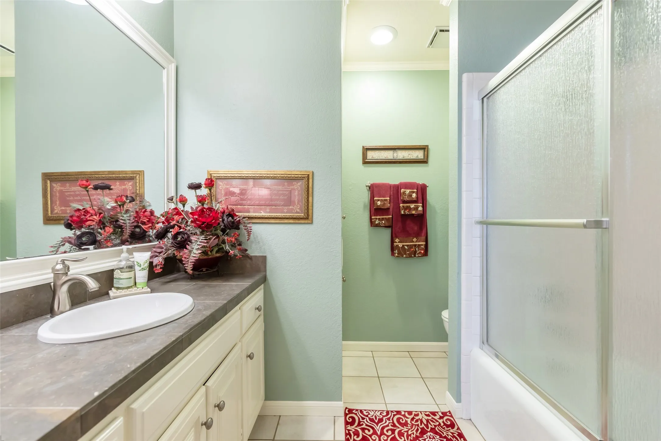 Bathroom featuring a built-in vanity with an undermount sink, a countertop, and cream-colored cabinetry with hardware