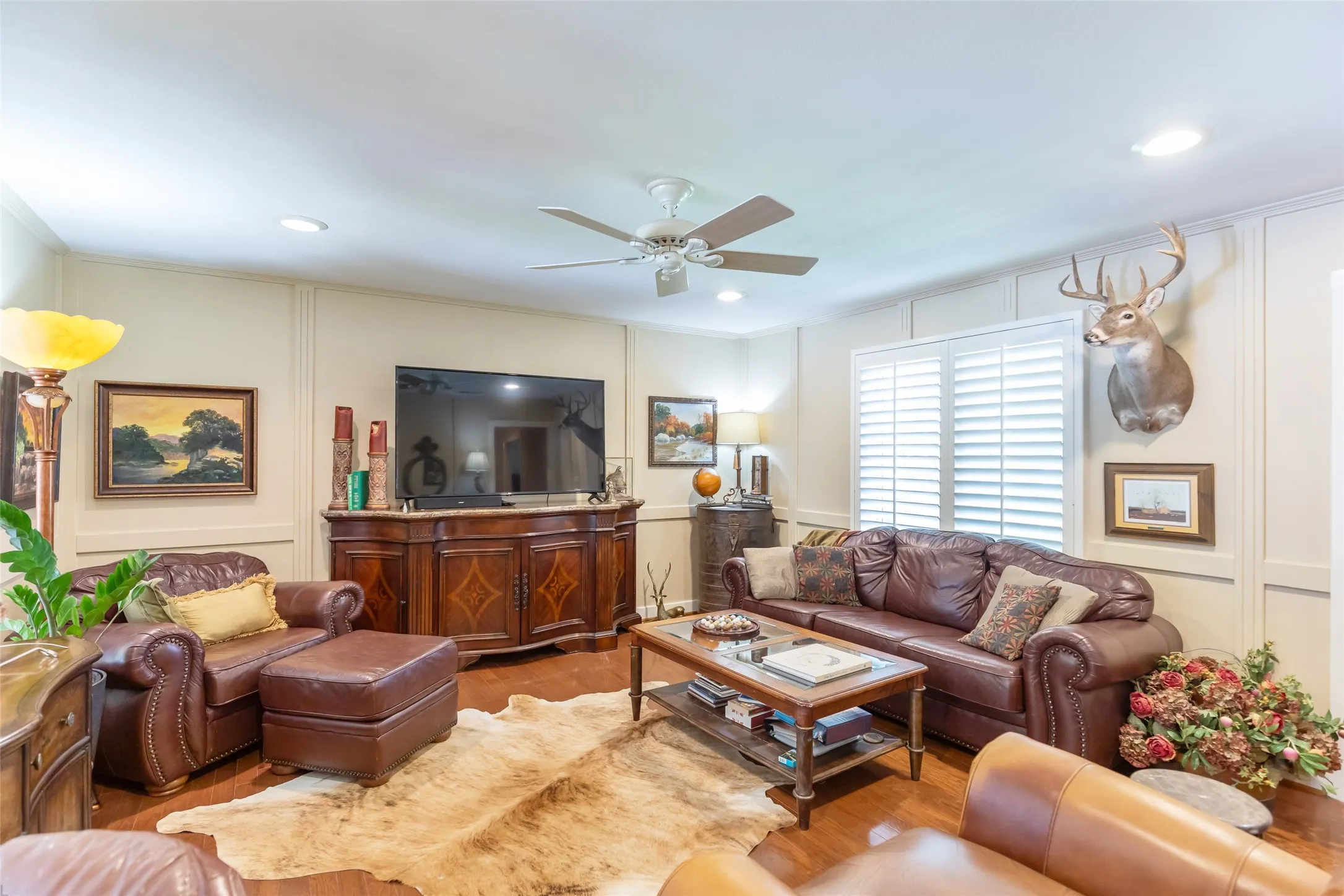 Wood-finish flooring, recessed lighting, ceiling fan, white paneled walls, and interior plantation shutters
