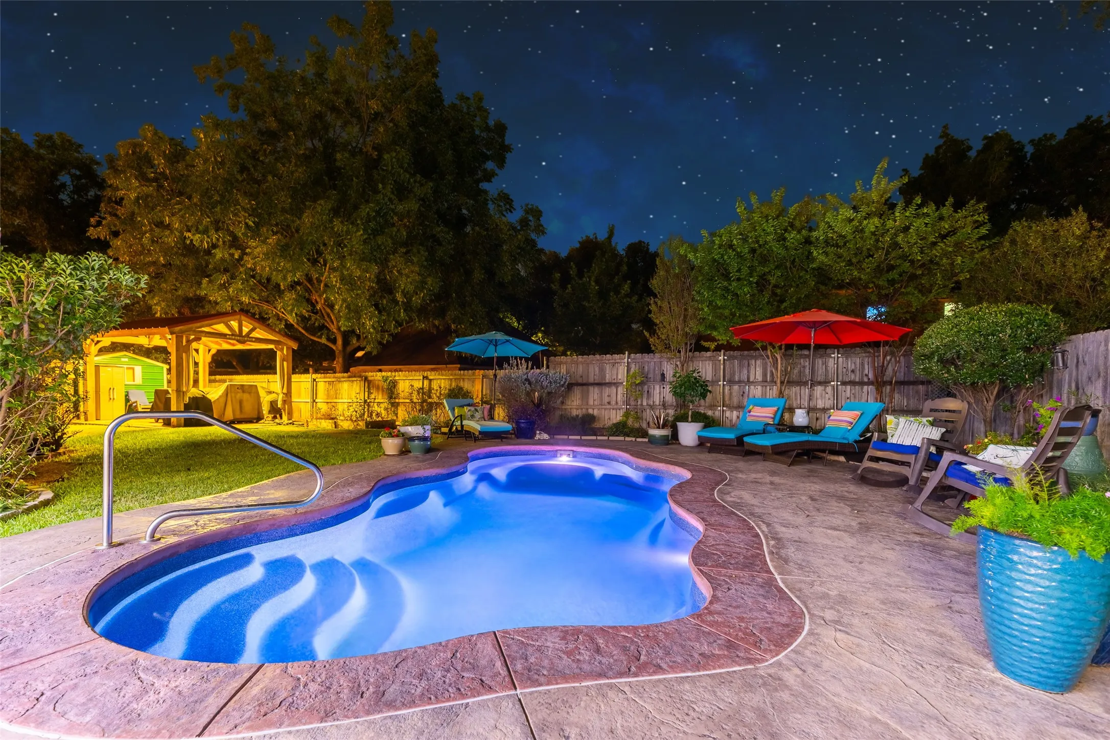 Freeform pool with integrated steps, surrounded by a stamped concrete patio