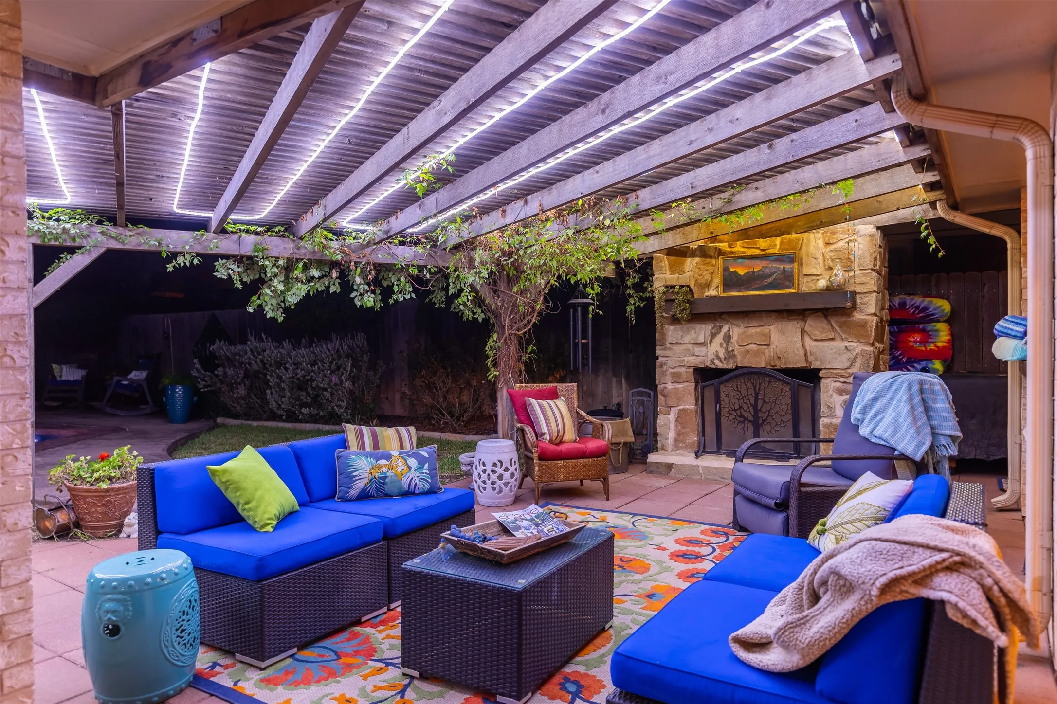 Patio featuring a wooden pergola with integrated lighting, a stone fireplace, and a paved surface