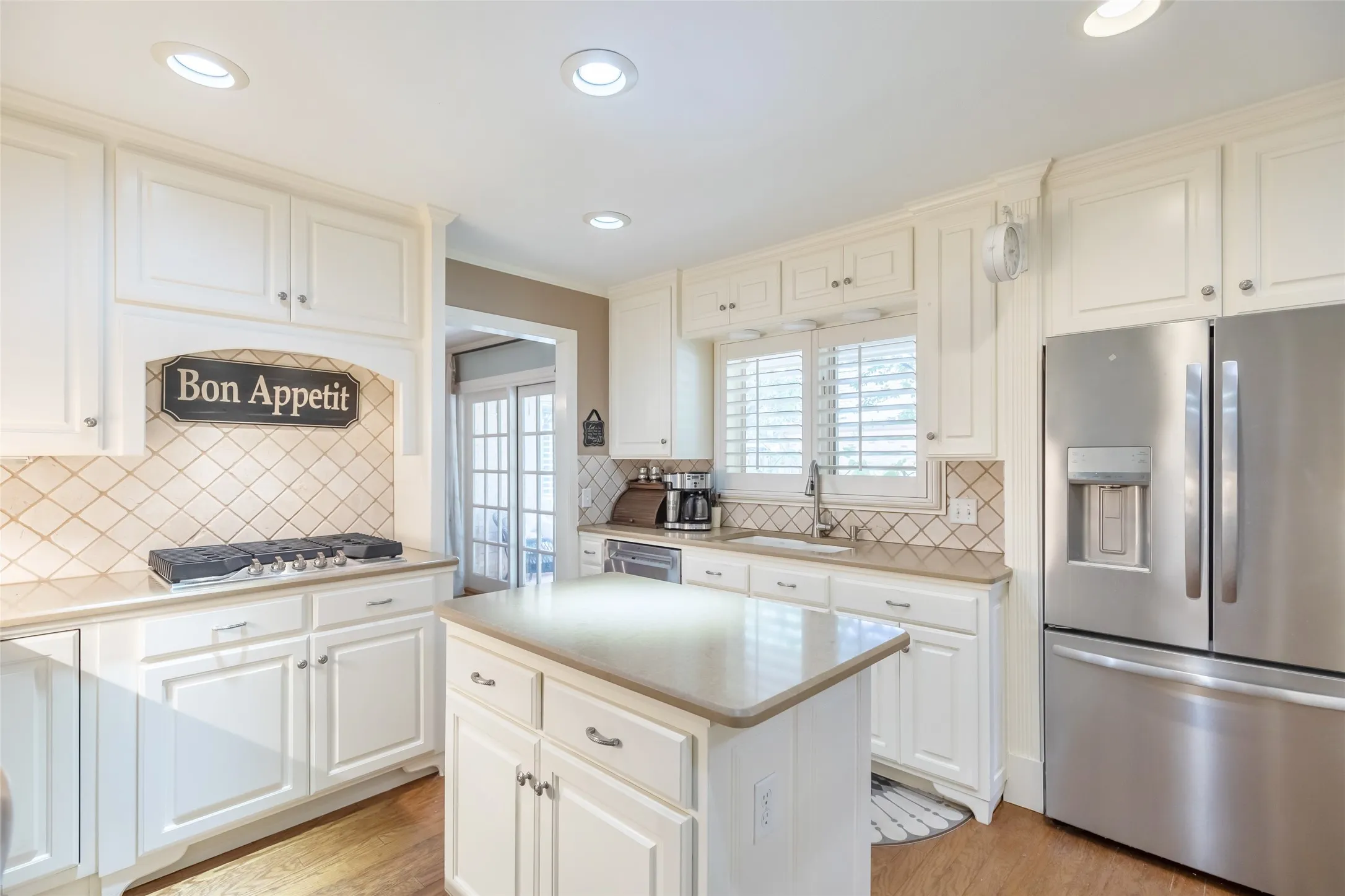 Kitchen featuring white cabinetry, a central island, stainless steel refrigerator, recessed lighting, and a tile backsplash