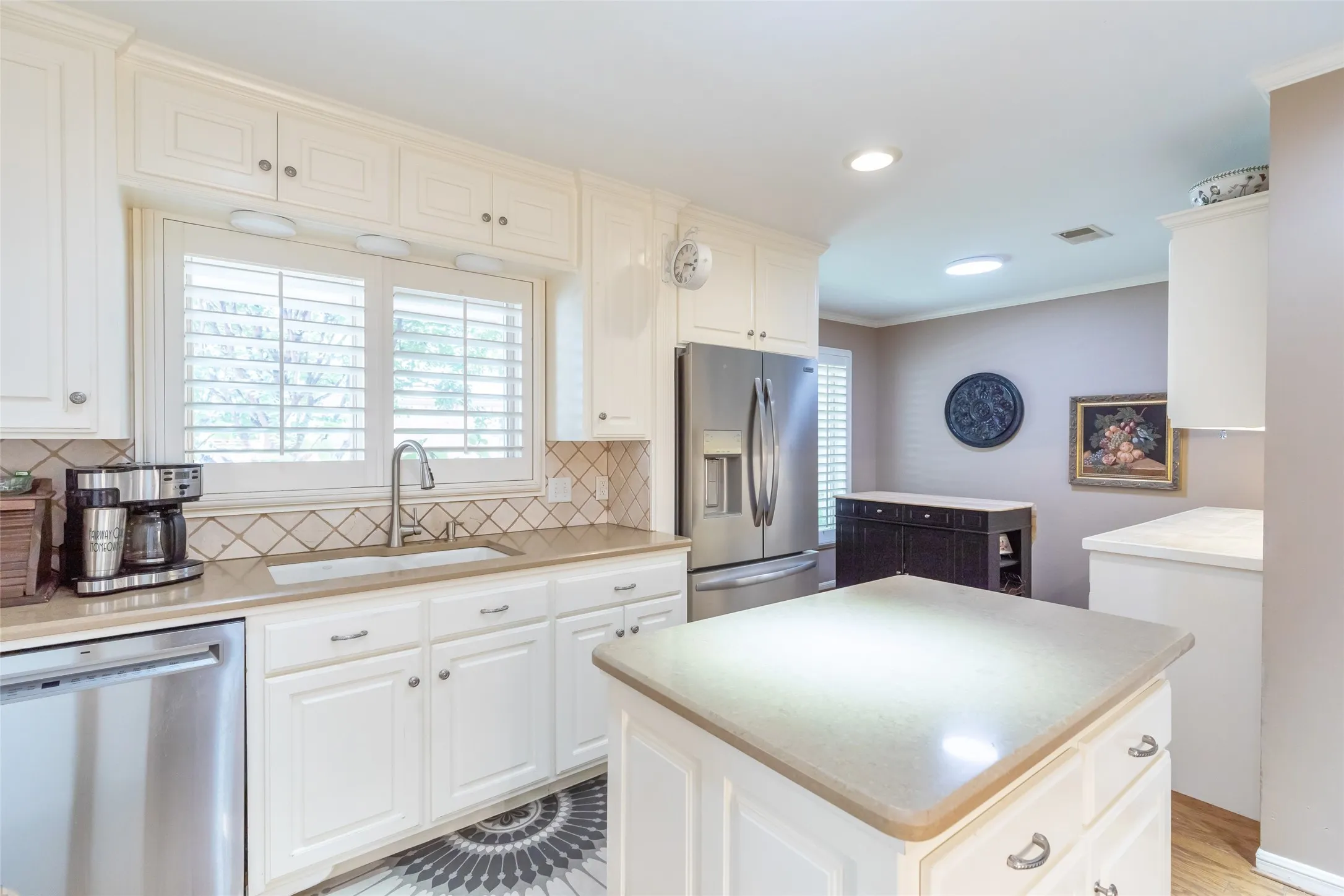 White cabinetry with brushed nickel hardware, stainless steel appliances, neutral countertops, and a tiled backsplash