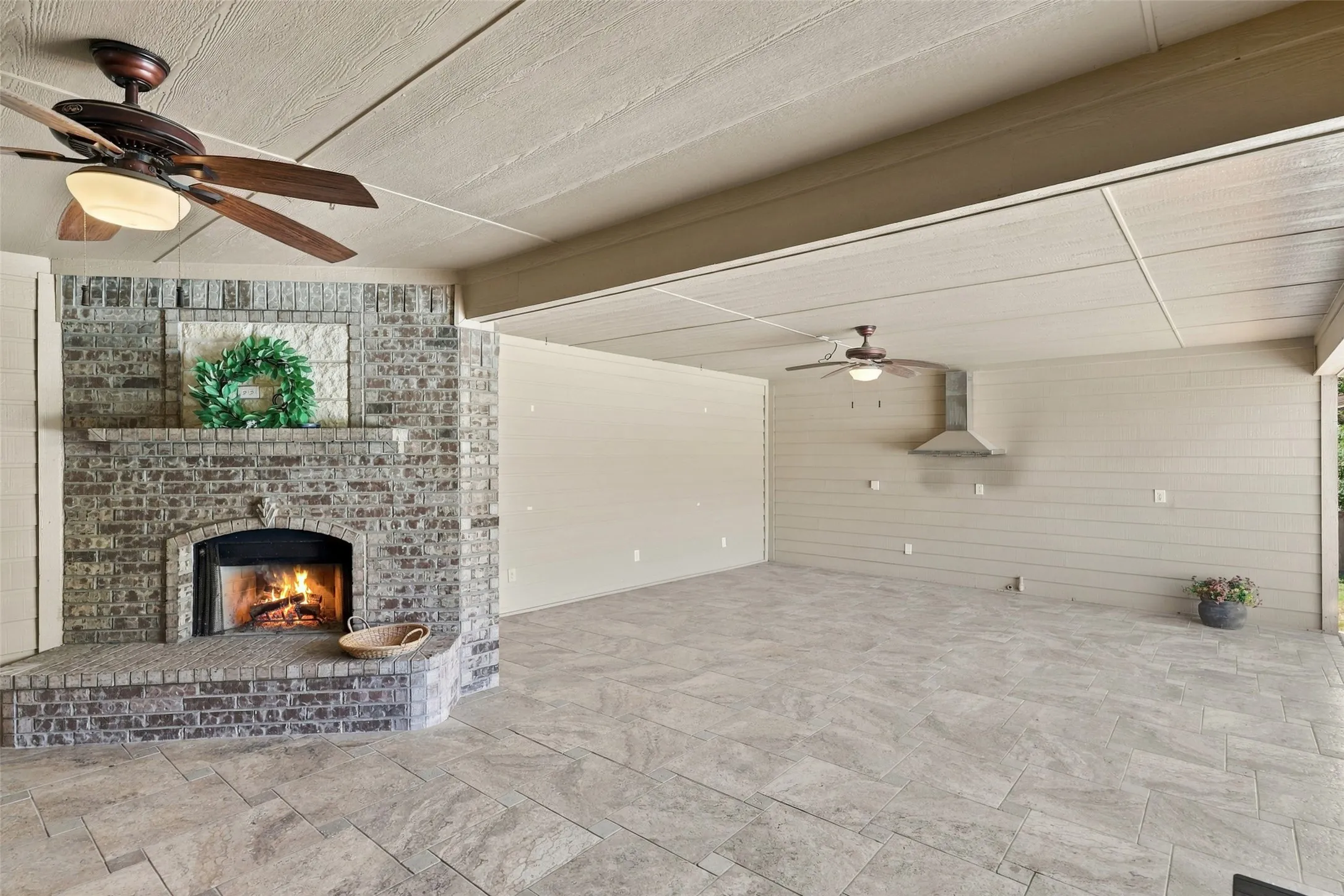 Outdoor Fireplace: Impressive brick fireplace anchors the spacious covered patio, complemented by tile flooring, ceiling fans, and room for multiple seating arrangements.