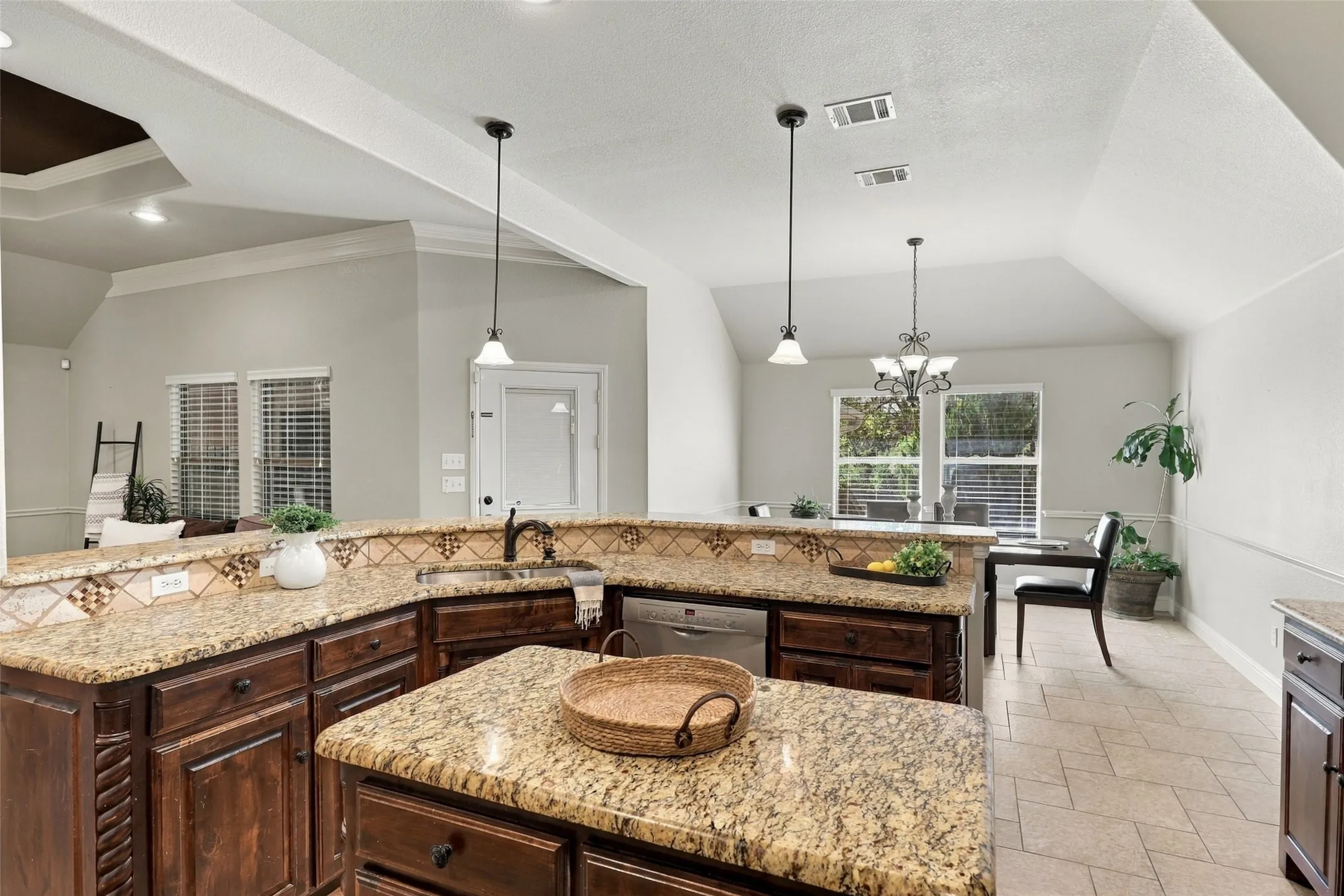 Kitchen & Dining: Open-concept design connects the kitchen and dining area, featuring expansive granite counters, pendant lighting, and abundant natural light.