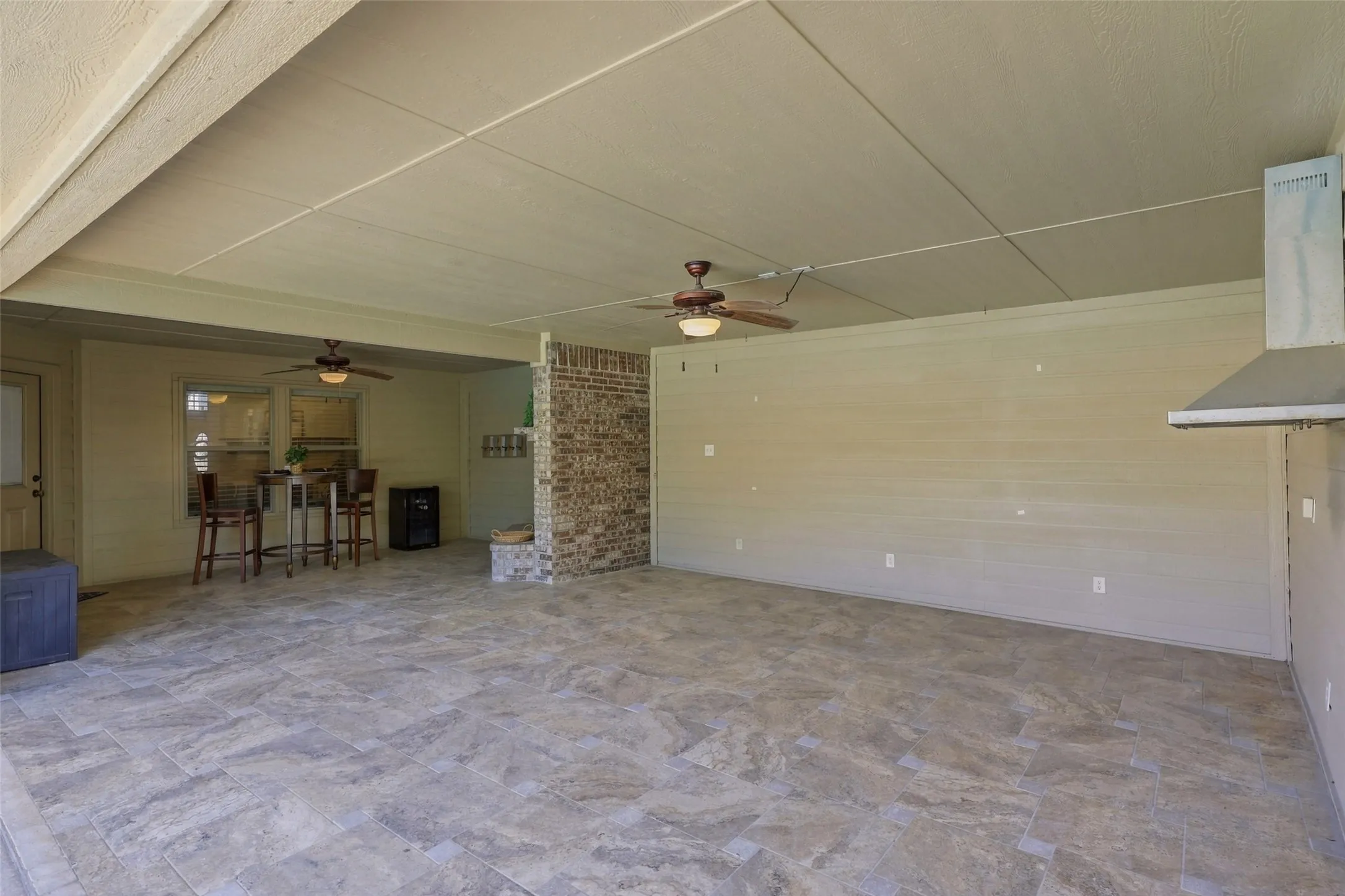 Covered Patio: Expansive outdoor living area features tile flooring, ceiling fans, and generous space for dining, entertaining, and relaxing.