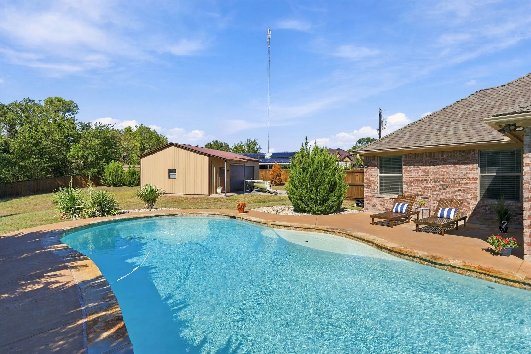 Backyard Pool: Beautifully designed swimming pool with curved edges, expansive decking, and convenient access to the workshop.