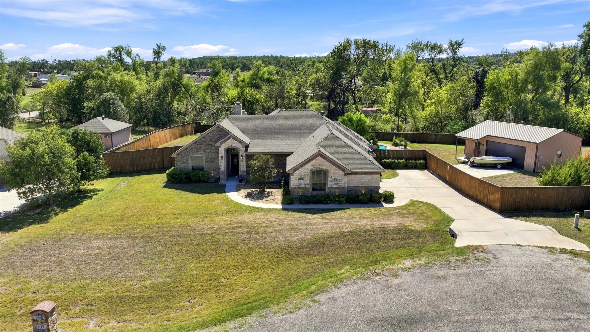 Aerial Front View: Beautiful brick and stone home situated on a spacious cul-de-sac lot, featuring a landscaped front yard, extended concrete driveway, and workshop.