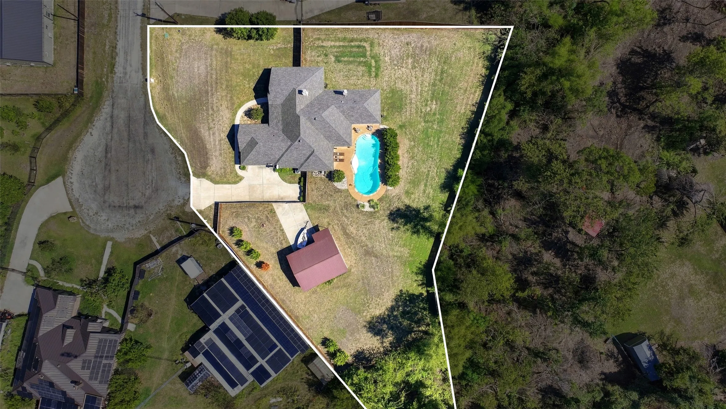 22. Aerial Property View: Overhead view showcases the expansive property layout, including the main residence, swimming pool, detached garage or workshop, and generous open yard space surrounded by mature trees.