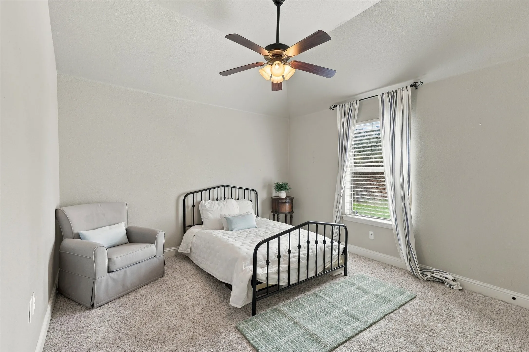 Secondary Bedroom: Comfortable bedroom offers vaulted ceilings, soft carpeting, a ceiling fan, and a window providing natural light.