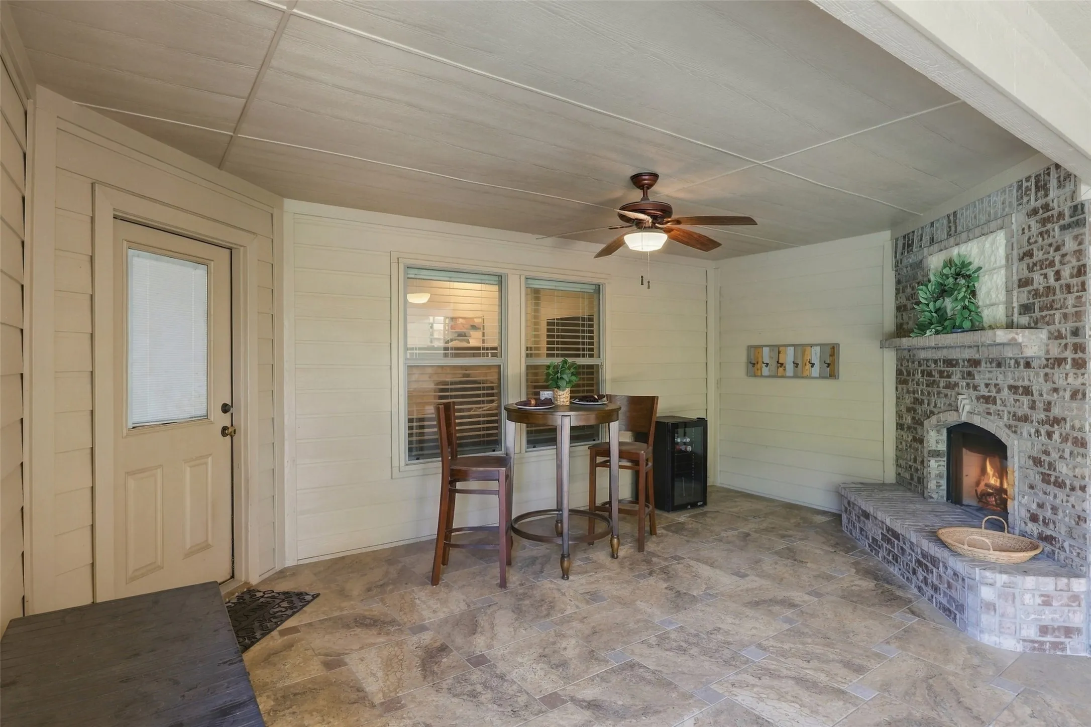 Outdoor Living Area: Covered patio offers a charming brick fireplace, comfortable dining space, and direct access to the home.